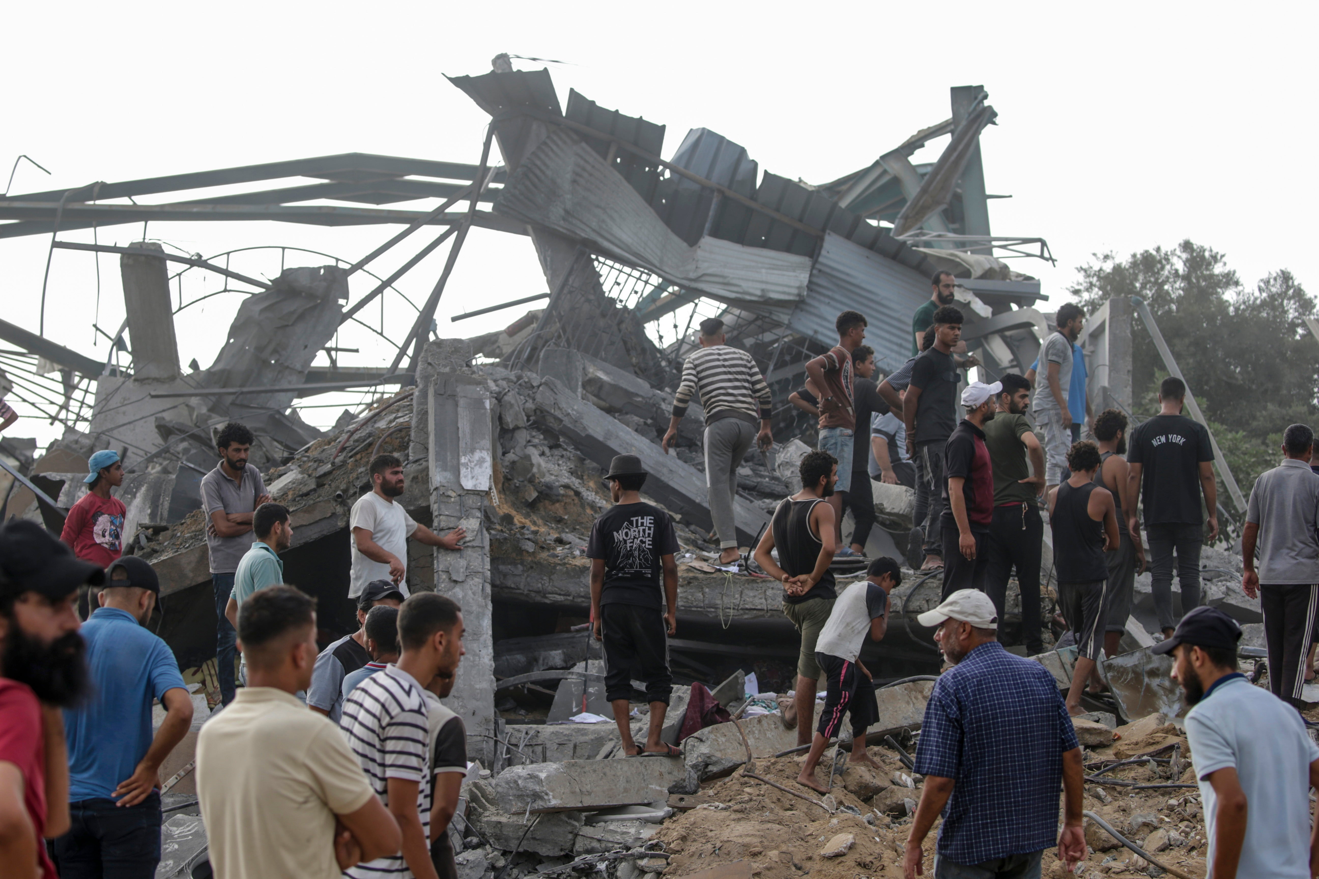 Palestinians search for bodies and survivors among the rubble of the destroyed building after the airstrike