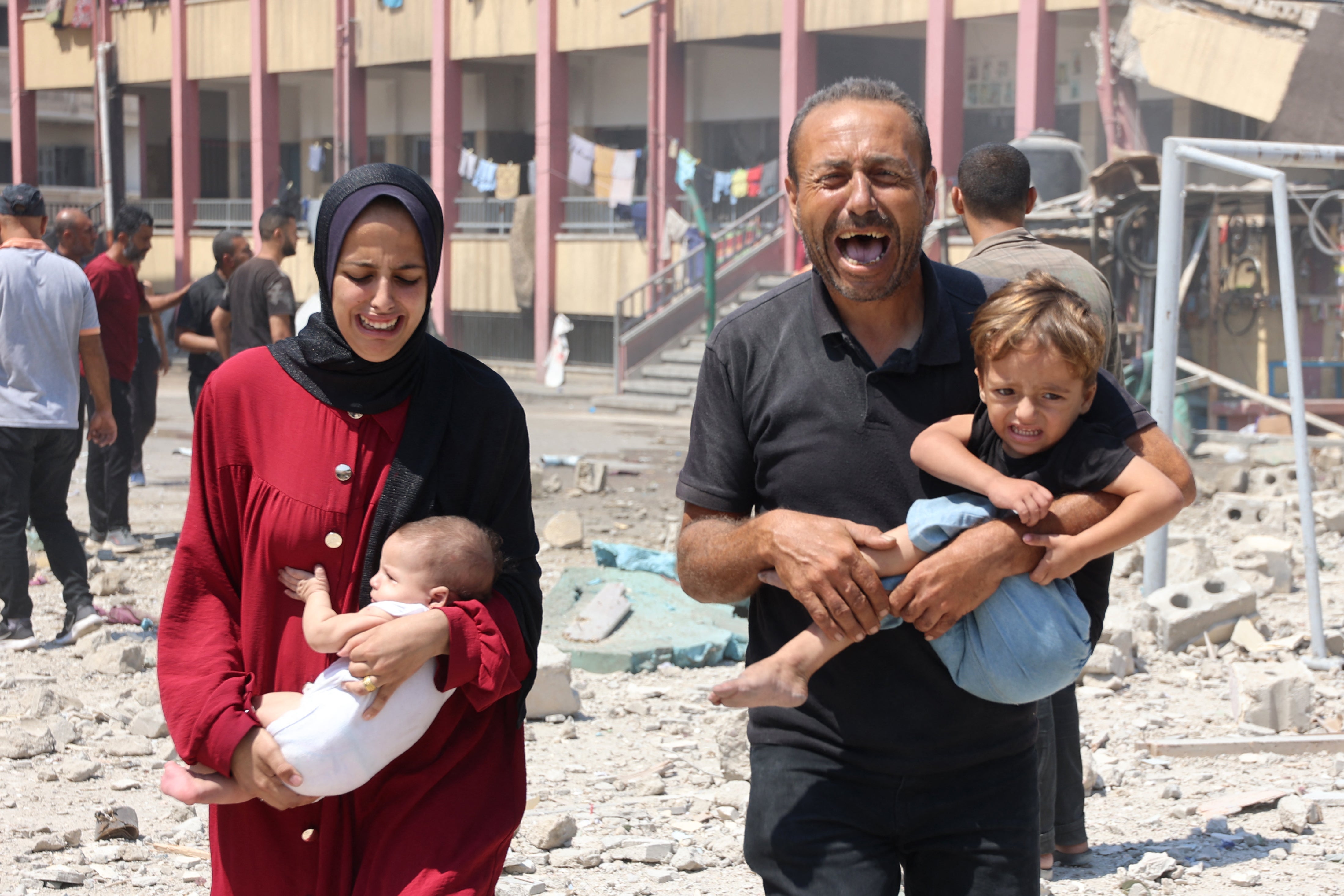 Palestinians carry their children as they flee after the Israeli strike on a school in Rimal, Gaza City