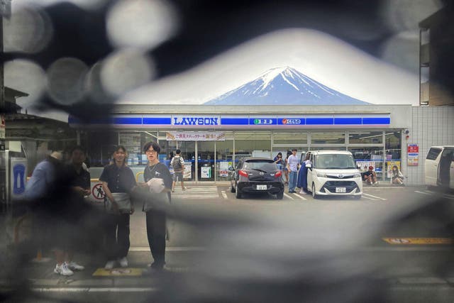 <p>Mt Fuji is seen through a hole on a black screen installed across from a convenience store in Fujikawaguchiko town, Yamanashi prefecture, central Japan on 24 May 2024</p>