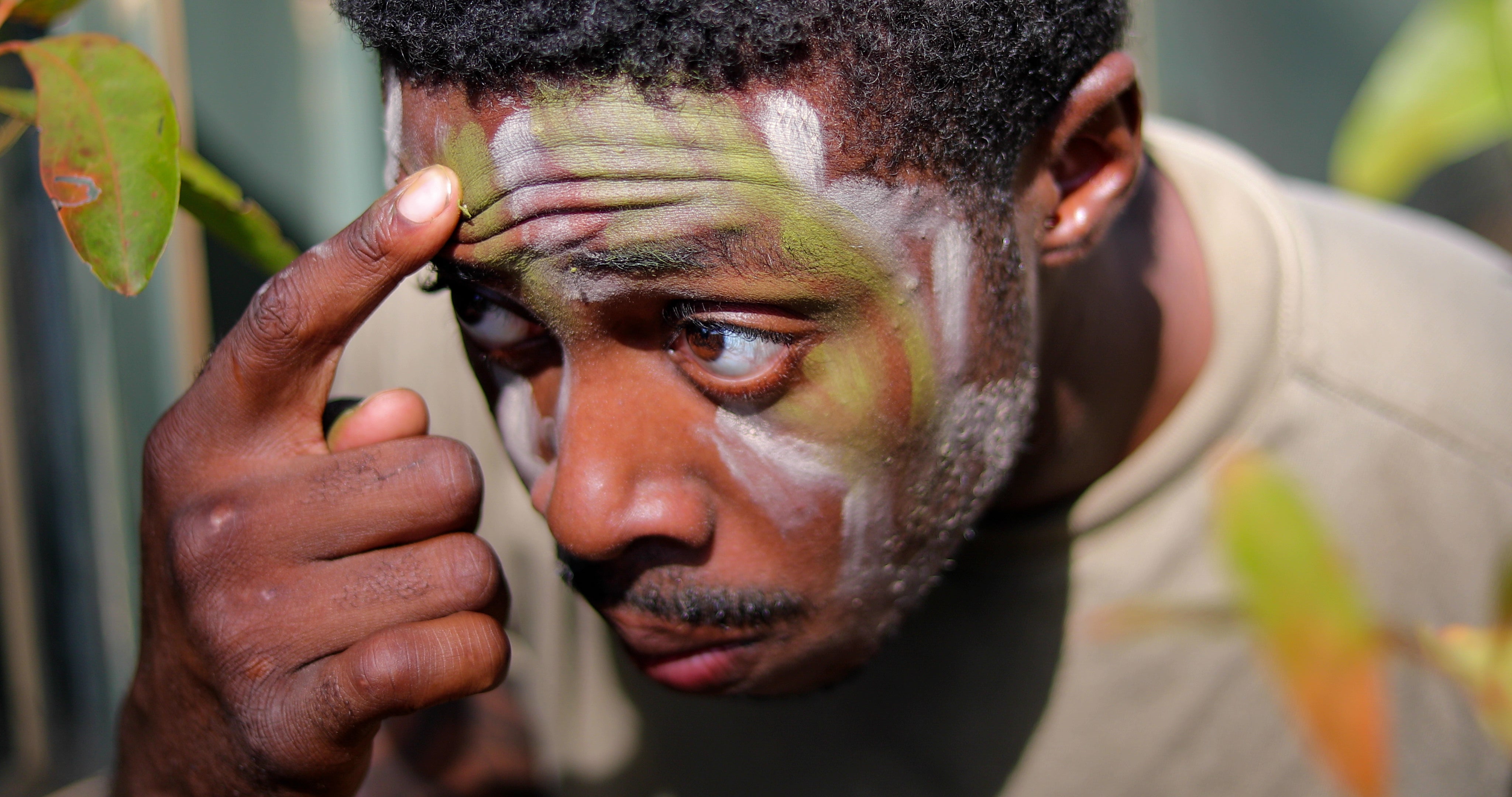 U.S. Army Pfc. Dewayne Johnson, a cavalry scout assigned to 3rd Squadron, 4th Cavalry Regiment, 3rd Infantry Brigade Combat Team, 25th Infantry Division, applies face paint during the Joint Pacific Multinational Readiness Center 24-01 at Helemano Military Reservation, Hawaii, Nov. 2, 2023.