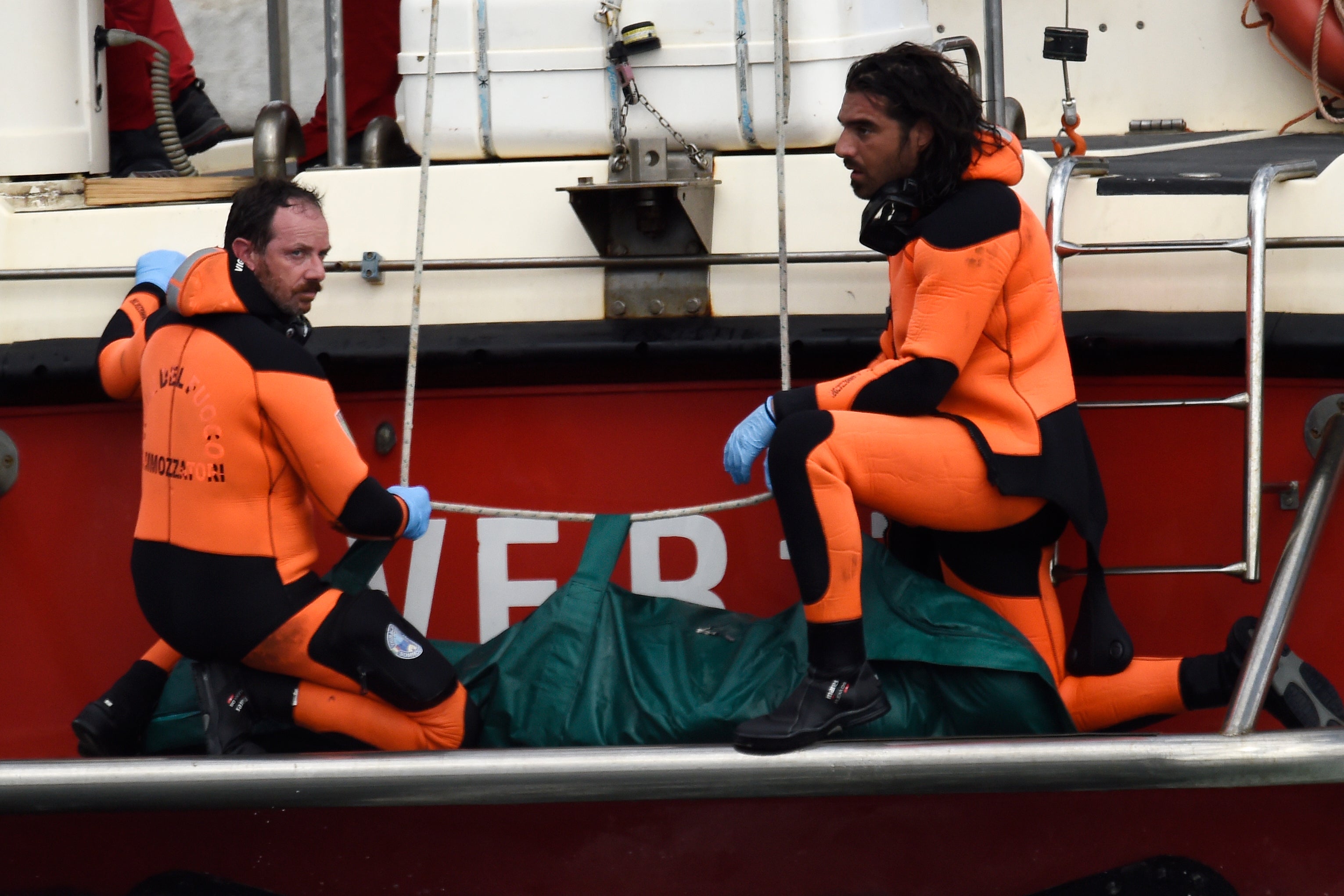 Italian firefighter scuba divers bring ashore the body of one of the victims on Wednesday