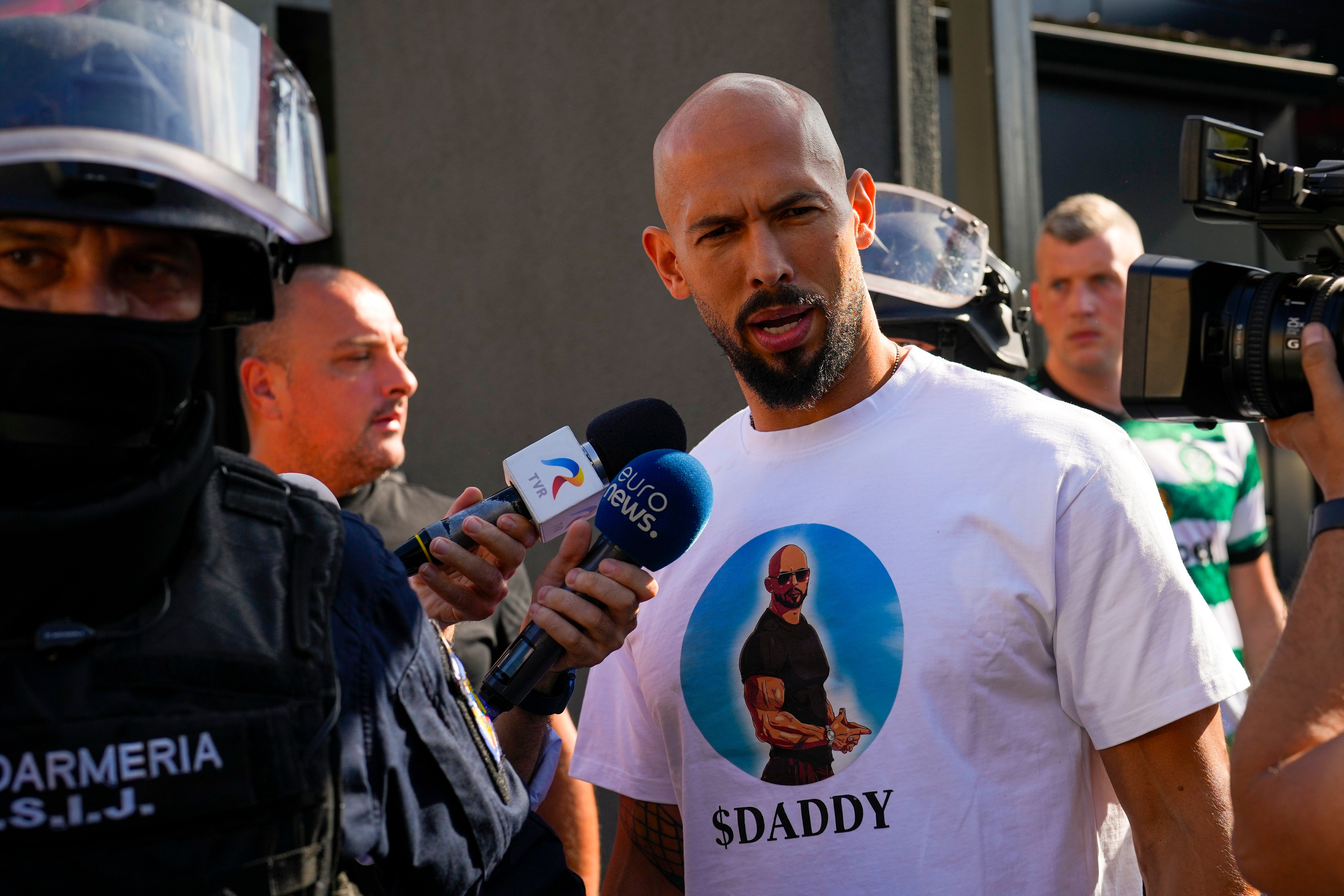 Andrew Tate talks to the media following a police search of his home in August