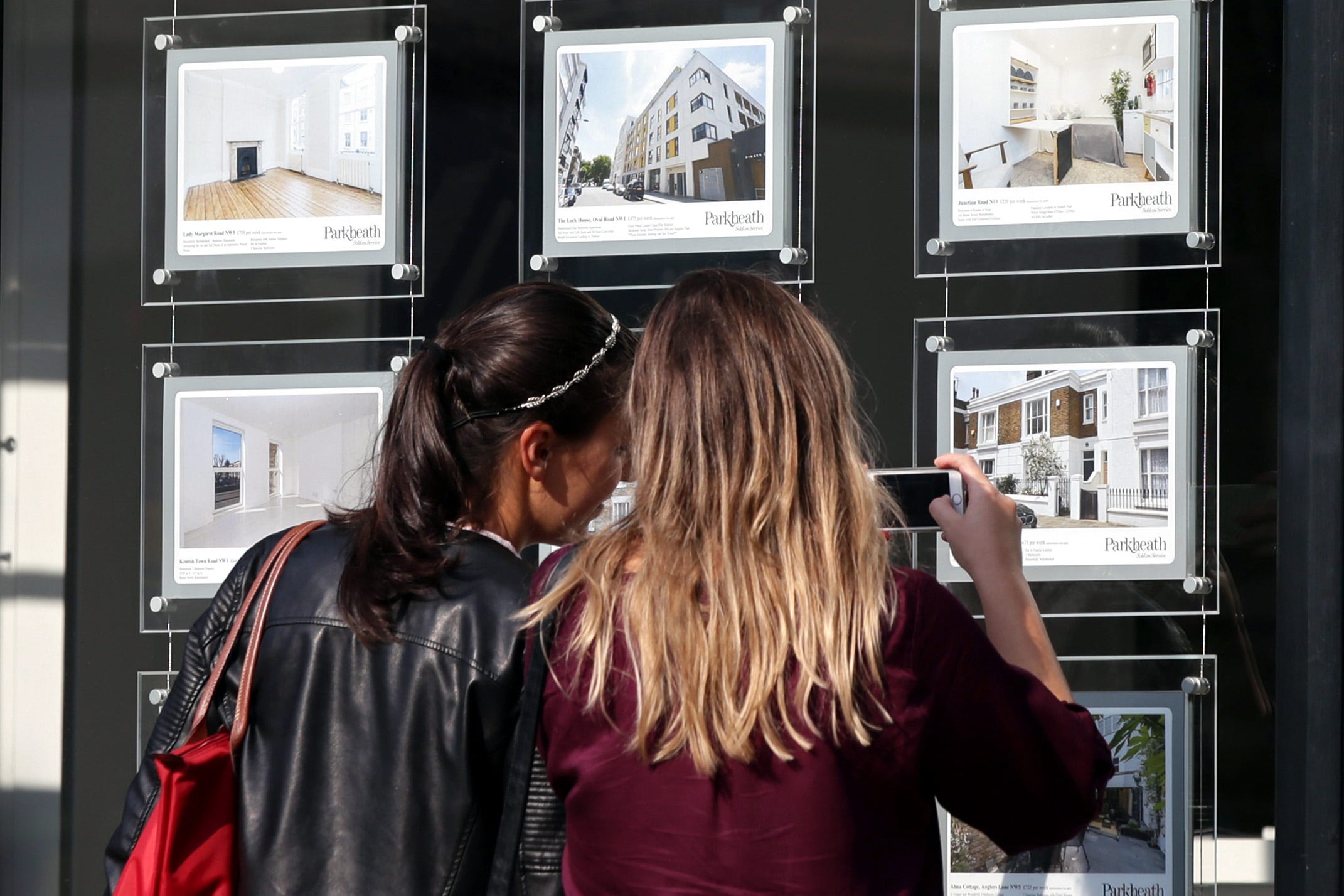 Two women look at property adverts in an estate agent’s window