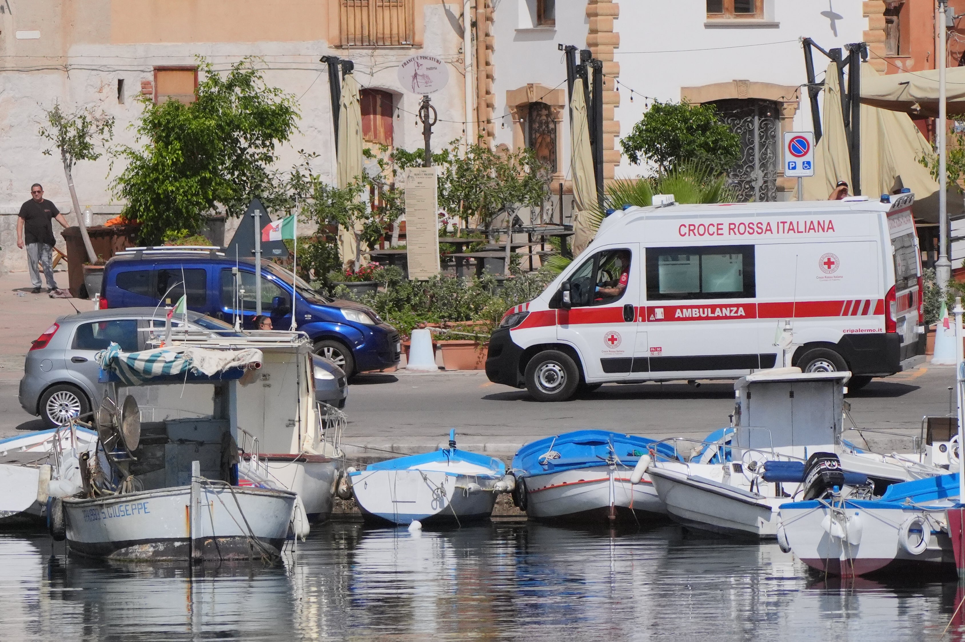 An ambulance carrying the fifth recovered body leaves Porticello Harbour to the mortuary