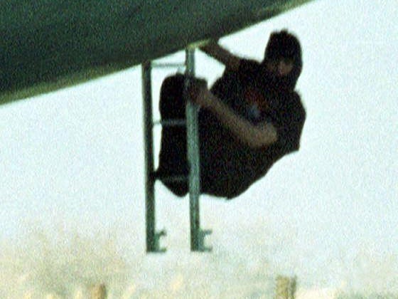 A hijacker holding a pistol climbs down a ladder from beneath the Indian Airlines aircraft cockpit in Kandahar, on 30 Afghanistan December 1999