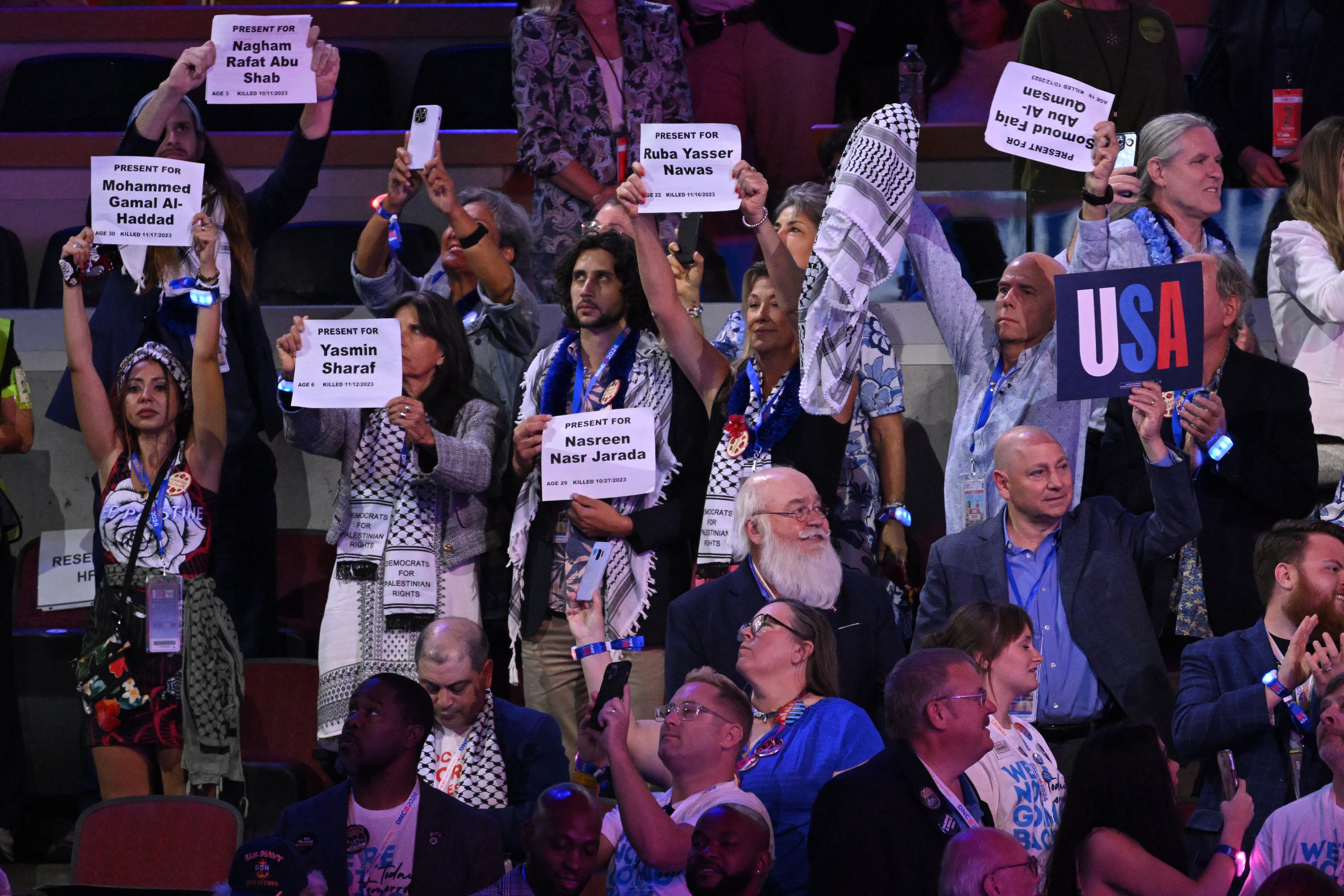 Delegates wearing keffiyehs hold up signs with the names of people who died in the Gaza war on the second day of the Democratic National Convention (DNC) at the United Center in Chicago, Illinois, on August 20, 2024.