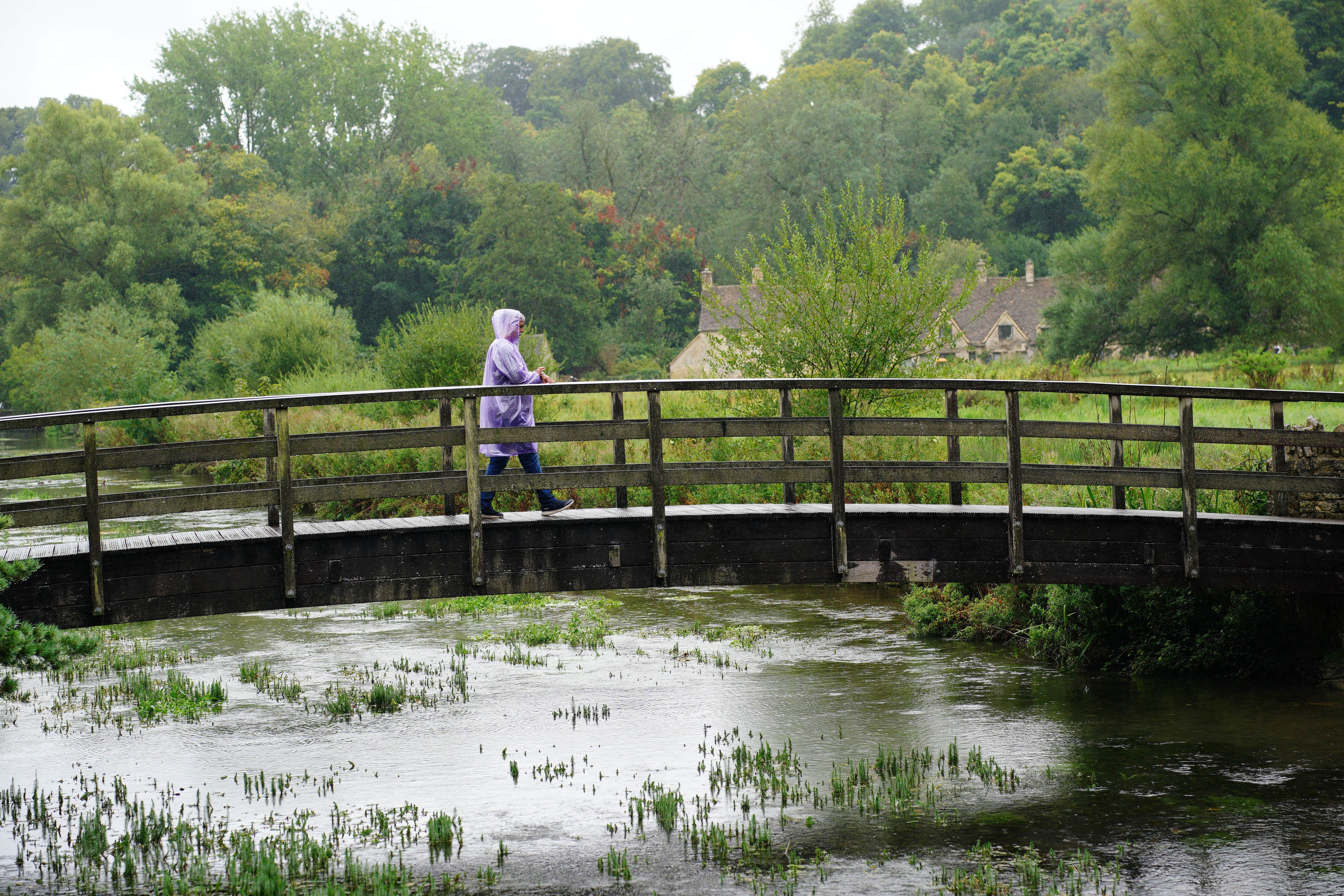 Visitors in the rainy weather at Bibury village in Gloucestershire (Ben Birchall/PA)