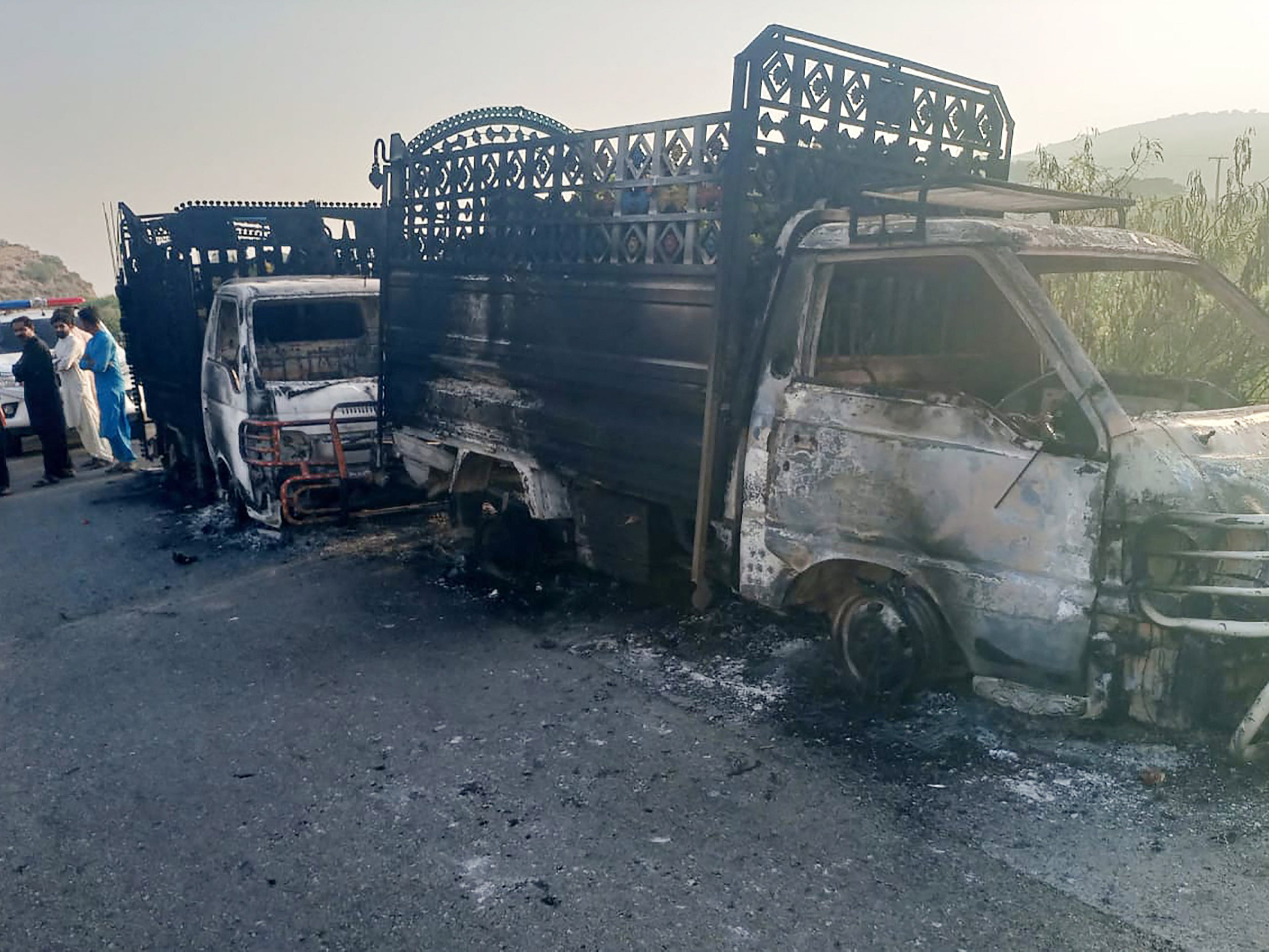 Security personnel stand near the charred vehicles at the shooting site on the national highway in Musakhail district, Balochistan province on 26 August 2024