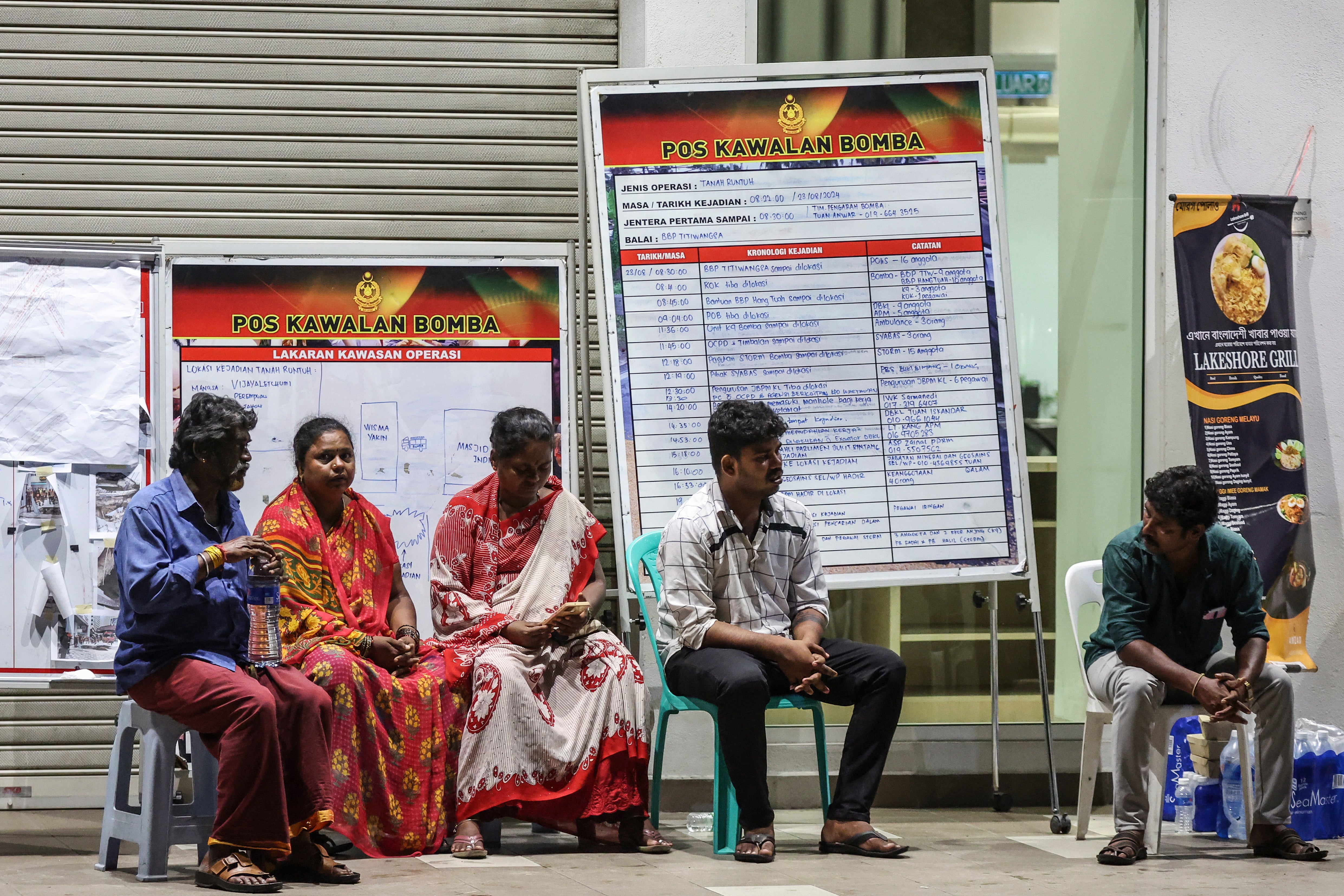 Relatives of an Indian woman who fell into an eight-metre-deep sinkhole wait for news near the accident site