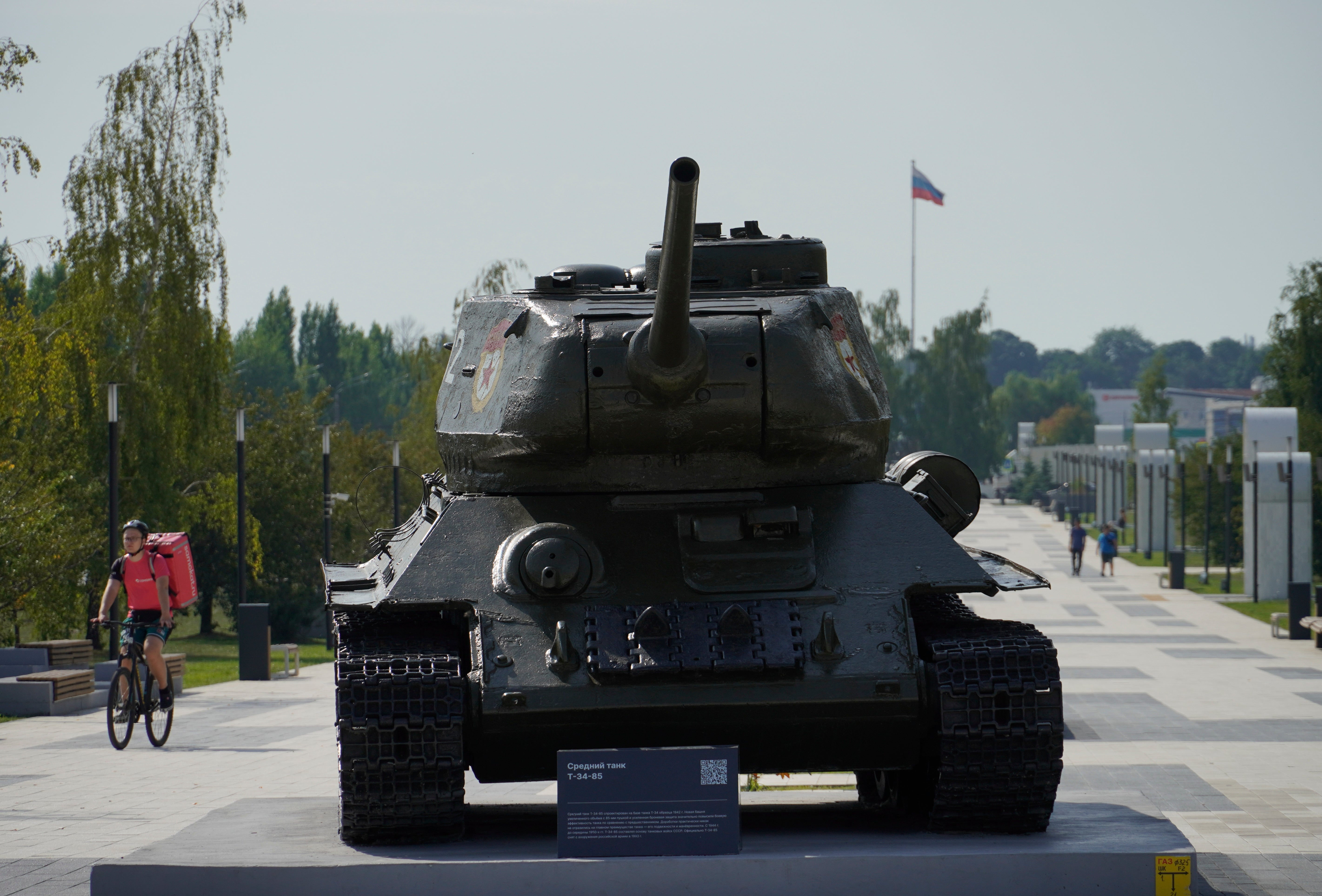 A delivery man rides a bicycle past a WWII t-34 tank in downtown Kursk