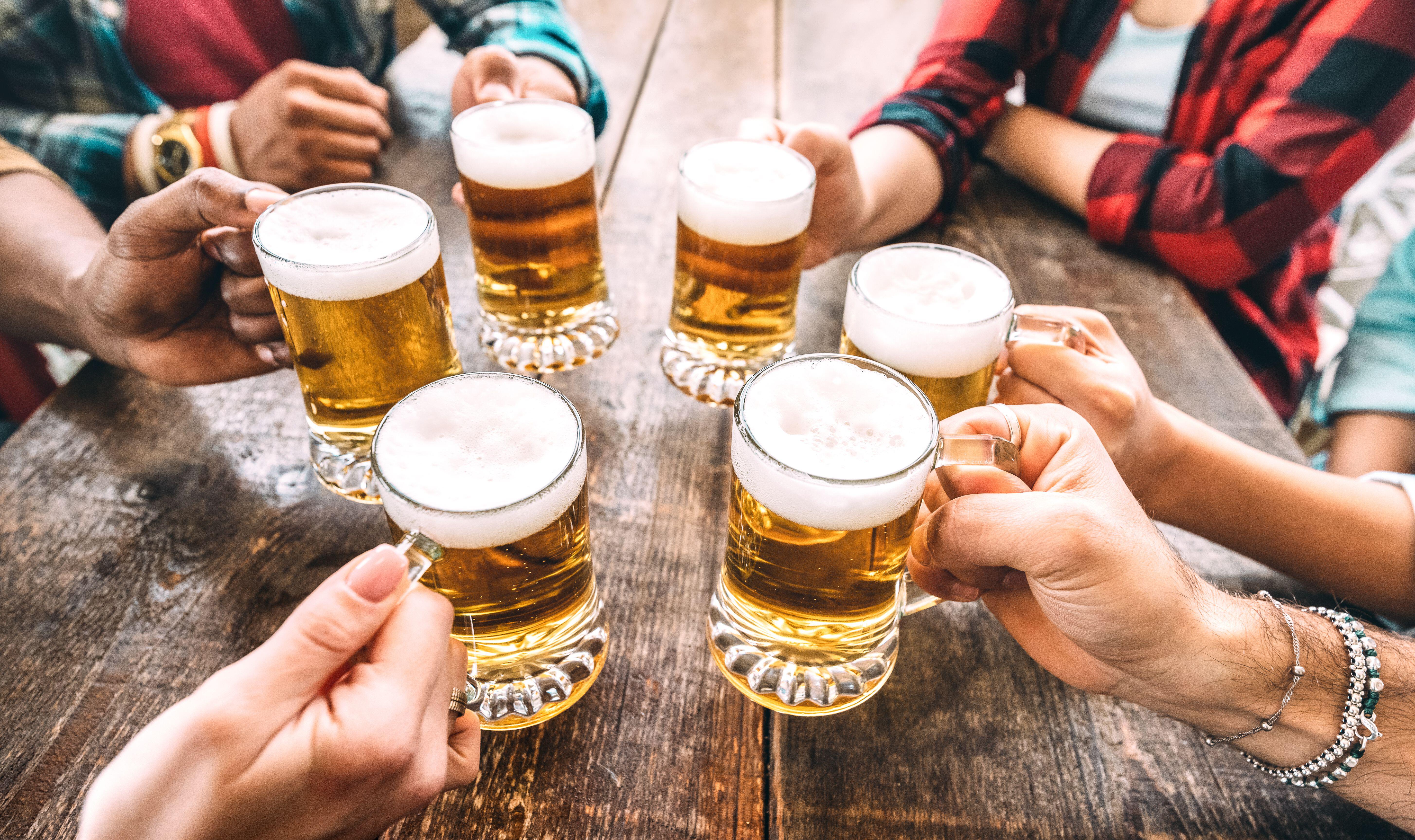 A group of six friends hands about to do a beer cheers with their pints (Alamy/PA)