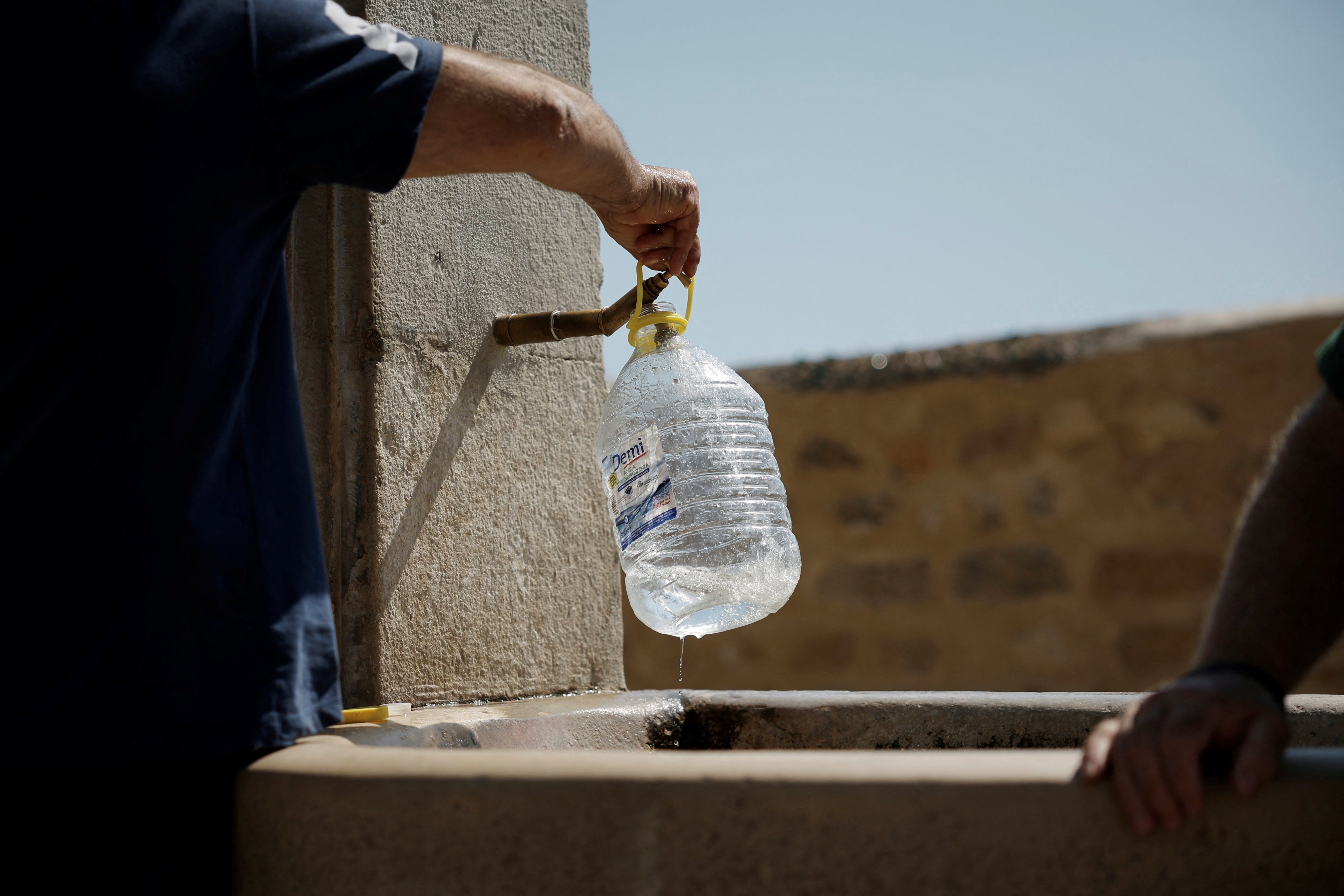 Salvatore Celauro fills a bottle with water from a fountain following a drought on the Italian island of Sicily, in Agrigento, Italy, August 25