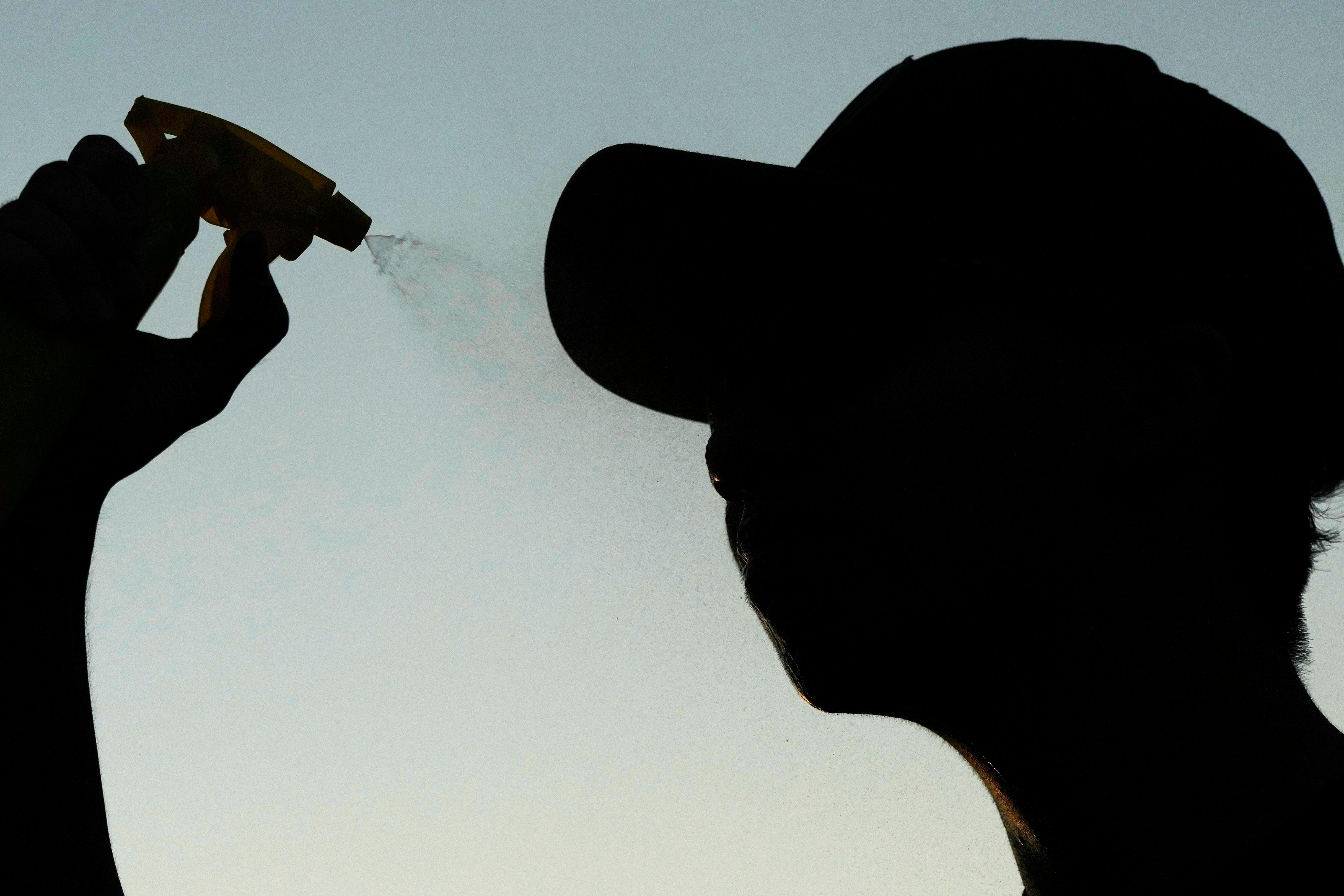 Person prays water to cool off after shooting hoops during a hot weather day