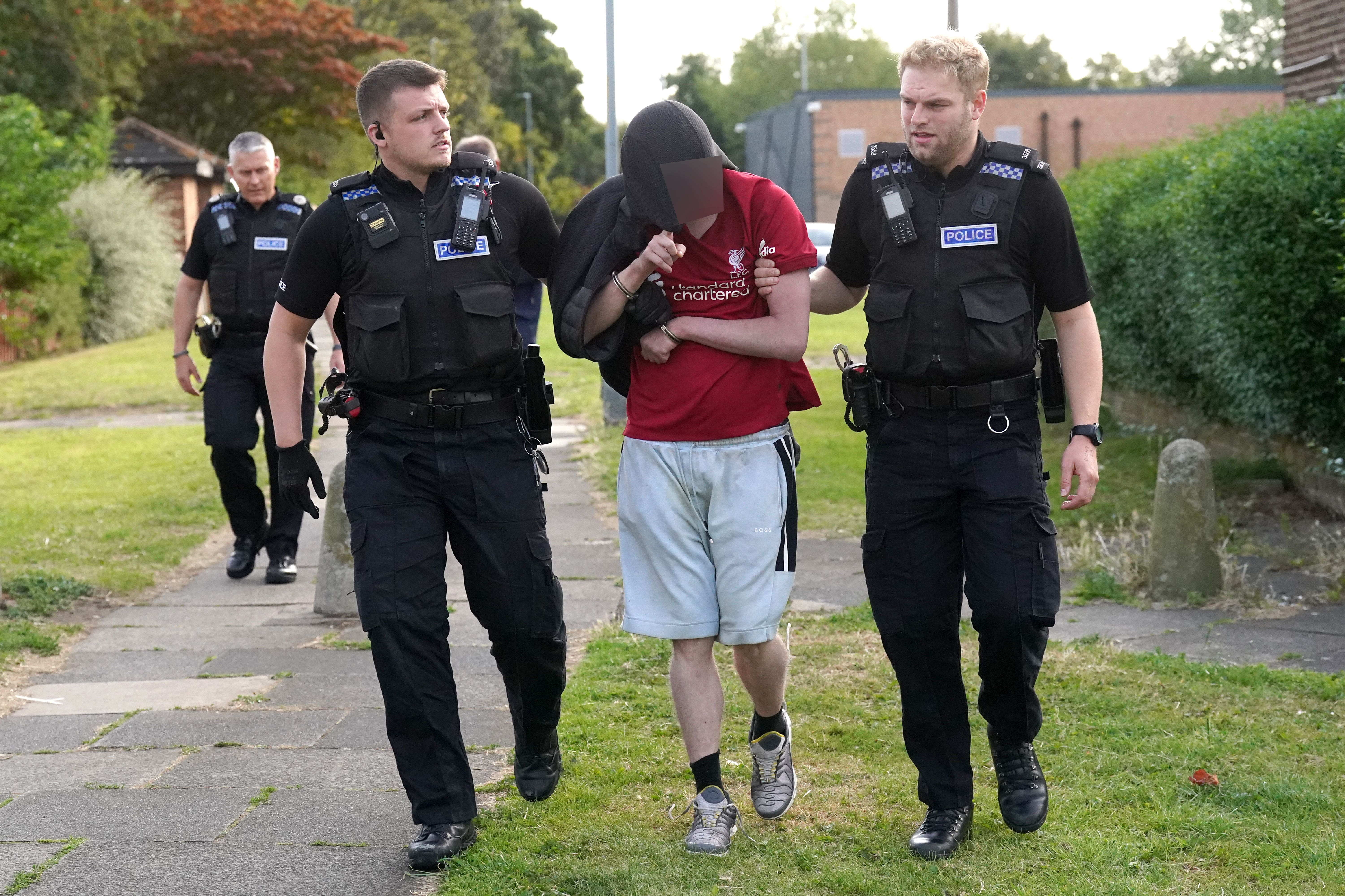 Cleveland Police officers escort a man they arrested in Middlesbrough during a day of action following the recent disorder (Owen Humpreys/PA)