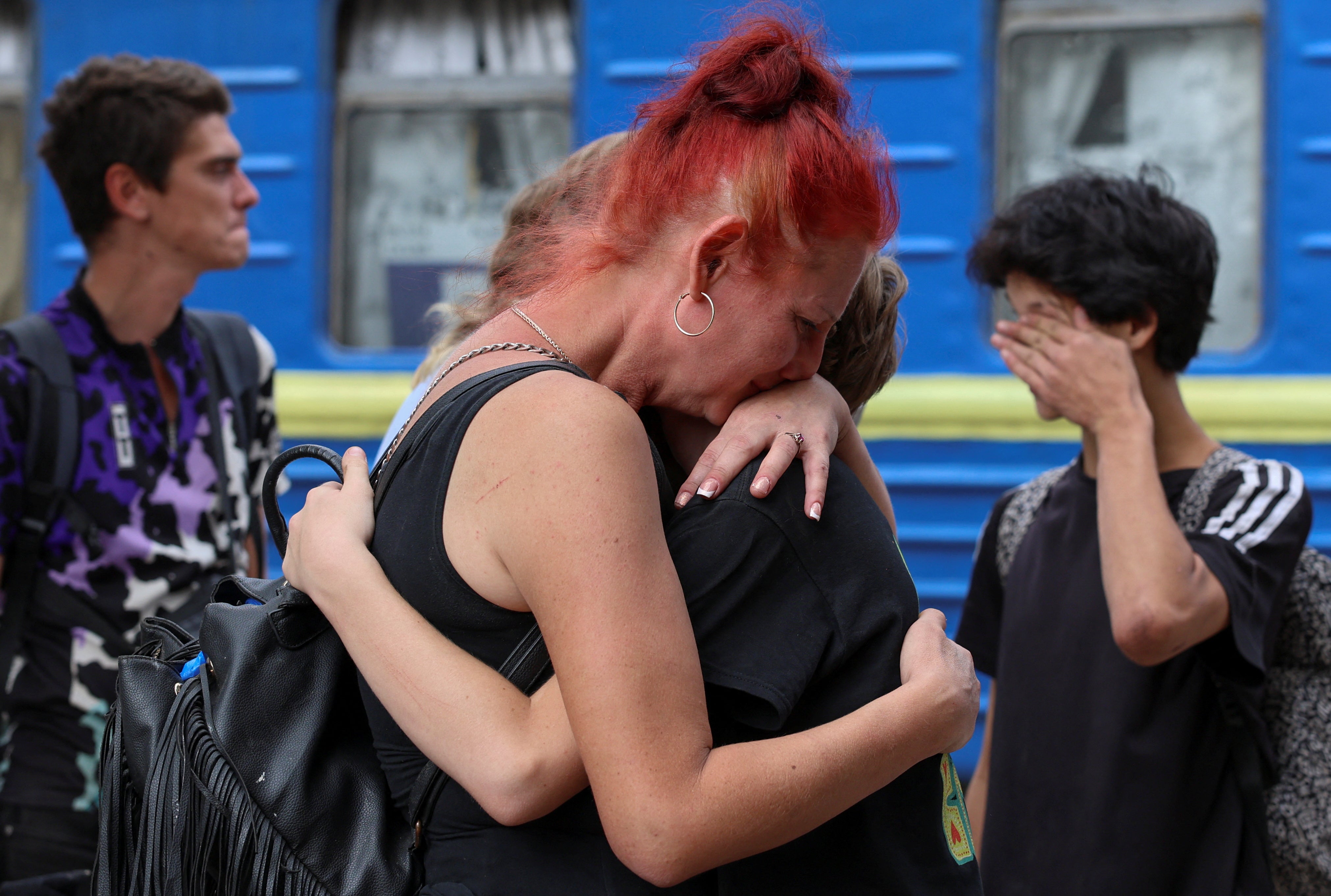 A woman embraces her relatives before they board an evacuation train to western Ukraine, in Pokrovsk