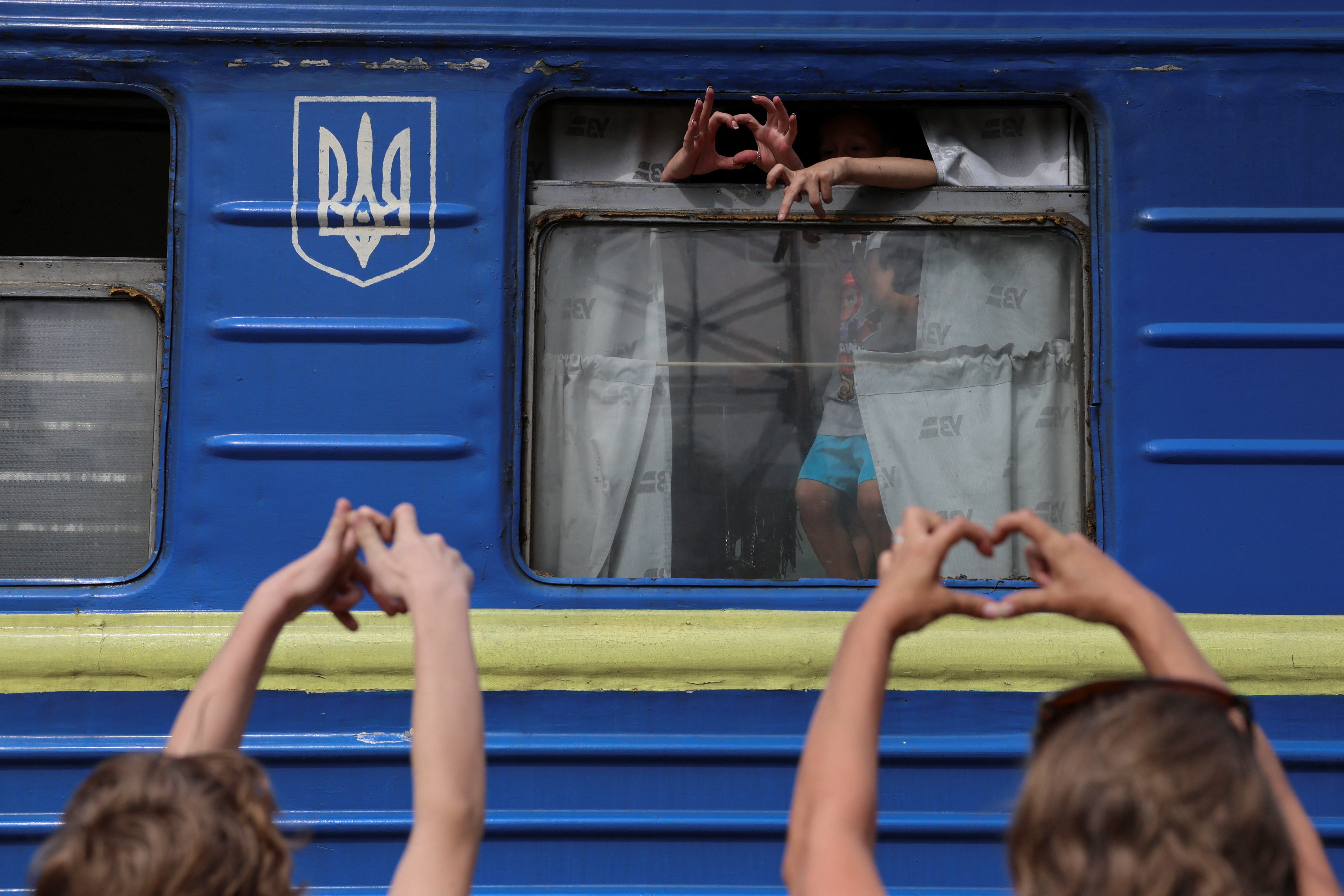 Relatives show each other hand hearts next to an evacuation train to Western Ukraine, amid Russia's attack on Ukraine, at a railway station in Pokrovsk