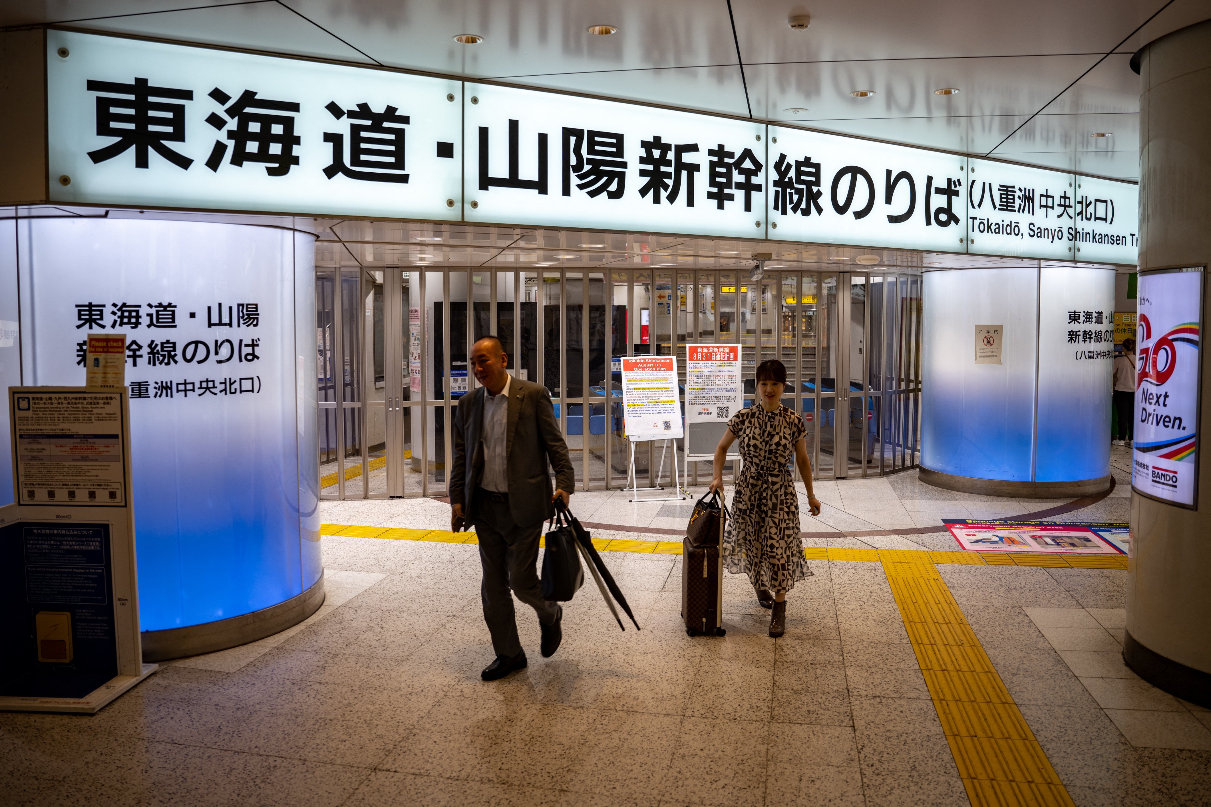 People walk in front of closed ticket gates for the Tokaido Shinkansen as train operations between Tokyo and Nagoya are suspended, in Tokyo Station