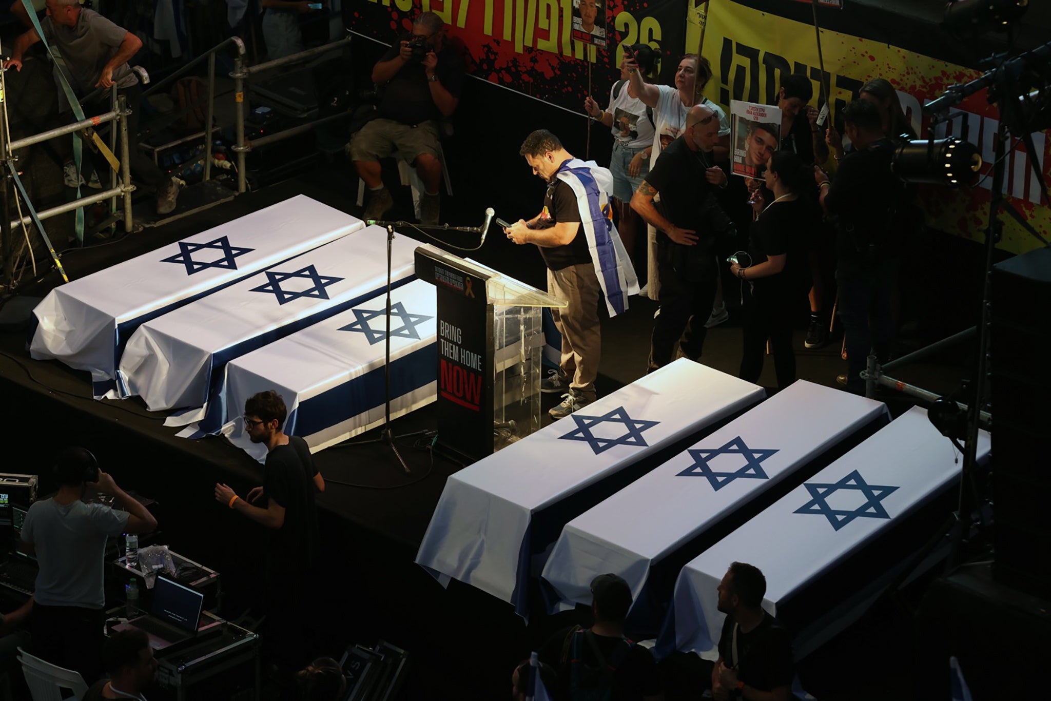 Demonstrators stand near six mock coffins