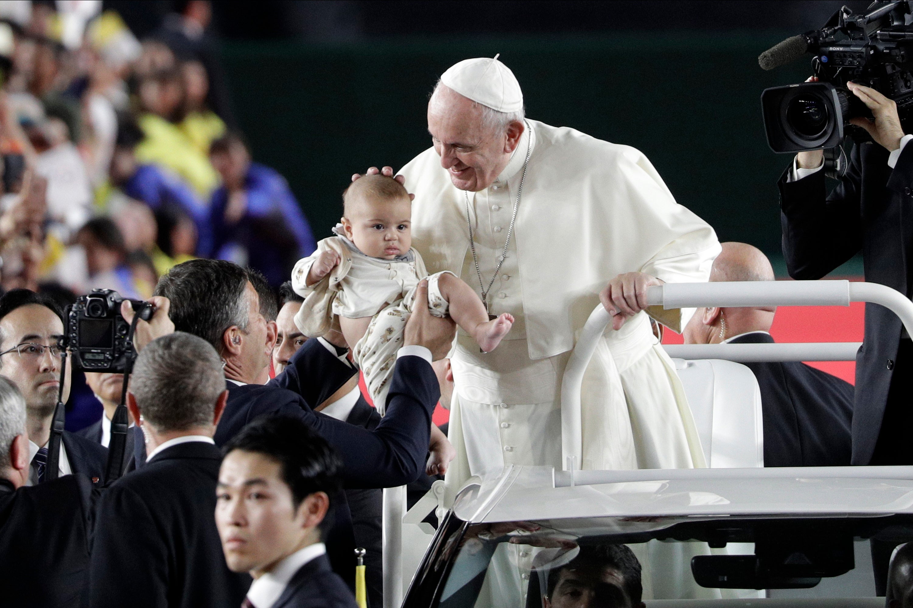 Pope Francis caresses a child in Popemobile as he arrives for Holy Mass at Tokyo Dome Monday, Nov. 25, 2019, in Tokyo