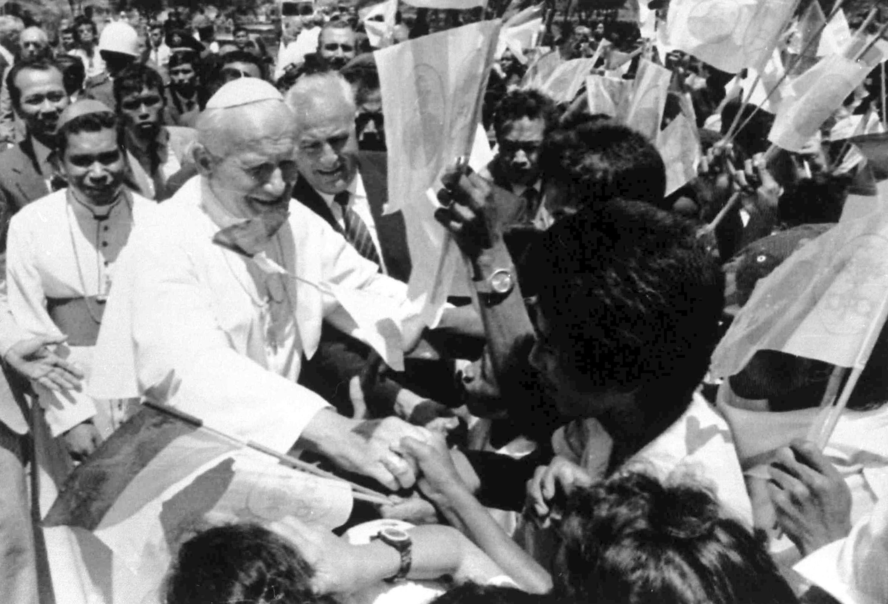 Pope John Paul II shakes hands with flag-waving local students upon his arrival in Dili, East Timor, Oct. 12, 1989