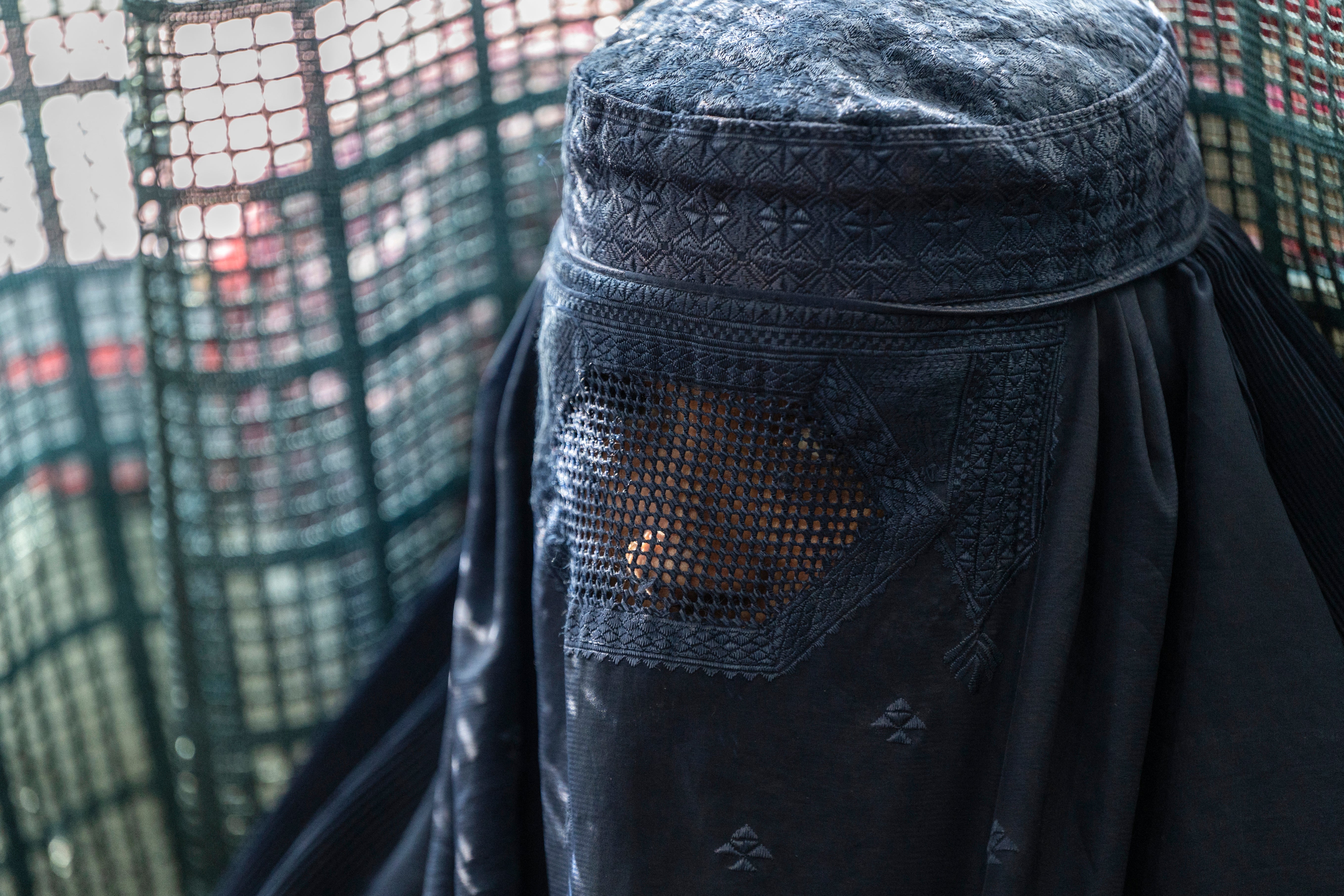 This photograph taken on 9 January 2024 shows an Afghan burqa-clad woman sewing clothes at a women's community center in Bagrami district on the outskirts of Kabul