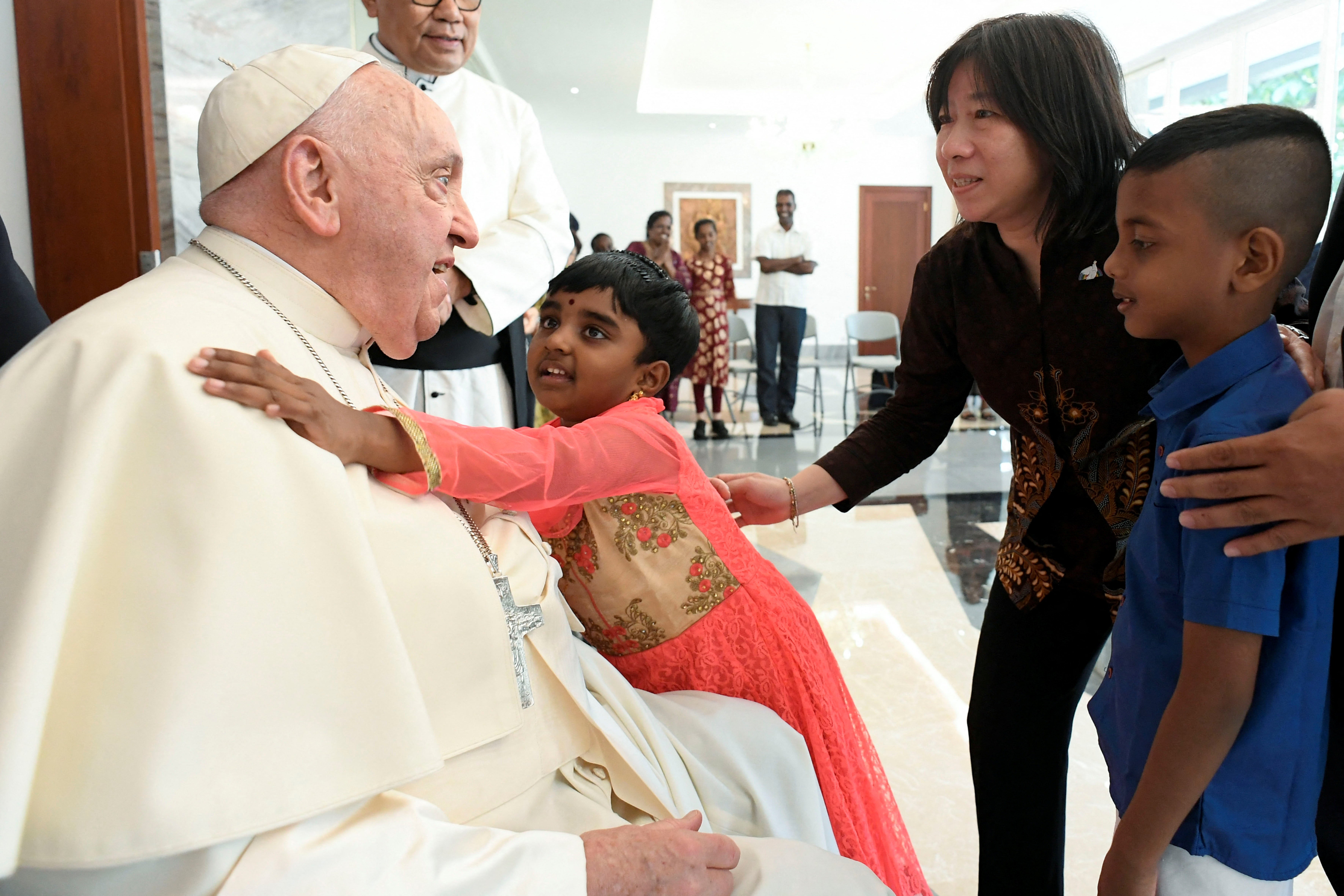 Pope Francis speaks with children as he meets with migrants during his apostolic visit to Asia