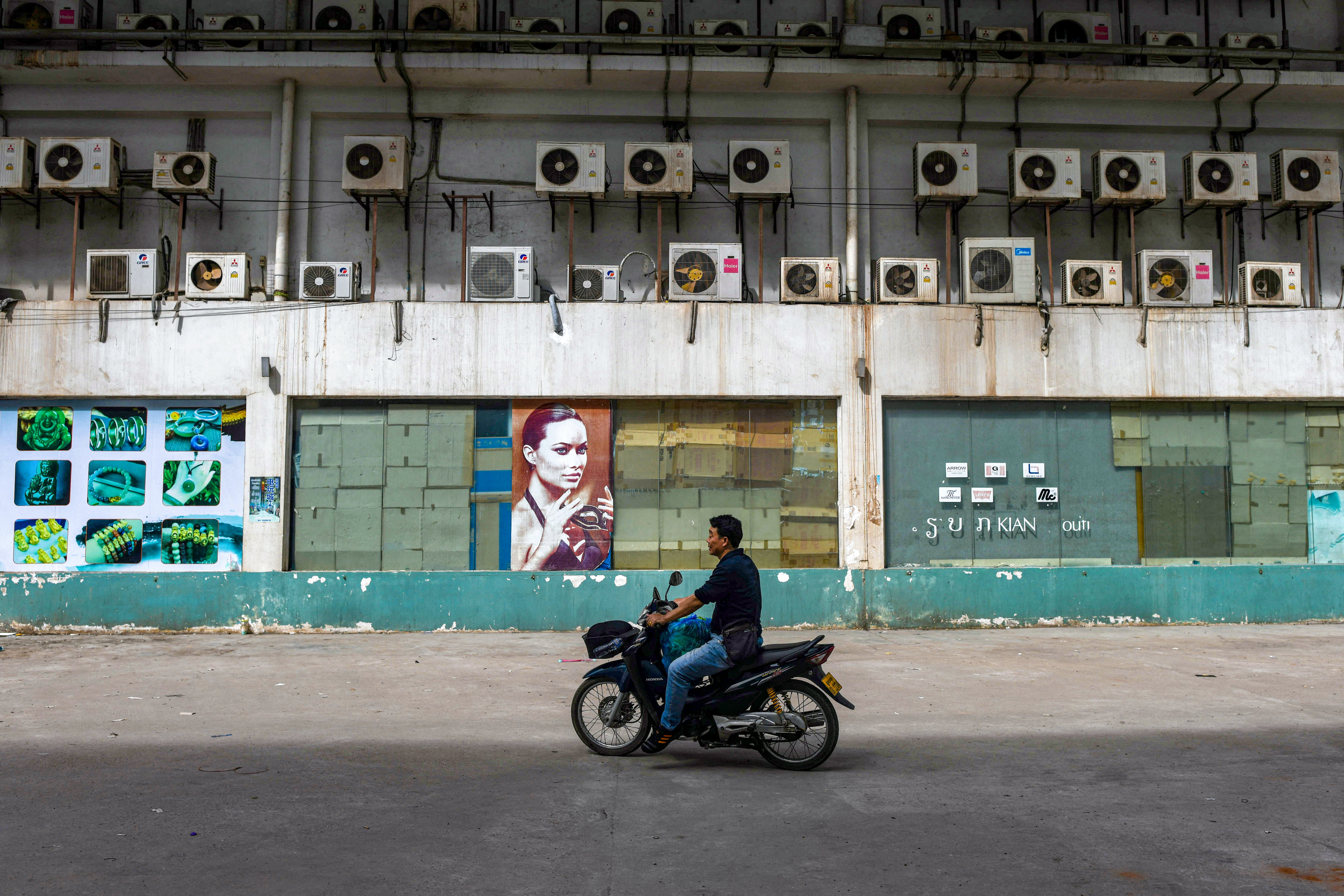 A man rides past condenser units of air conditioners installed on a building