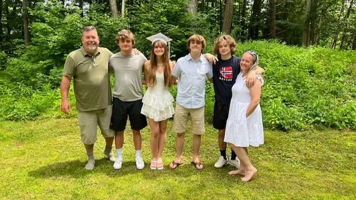 Joe Casey, far left, and his family pose in front of a wooded area. Casey, 51, is fighting for his life after contracting multiple mosquito-borne viruses, including Eastern Equine Encephalitis, West Nile virus, and St. Louis Encephalitis.