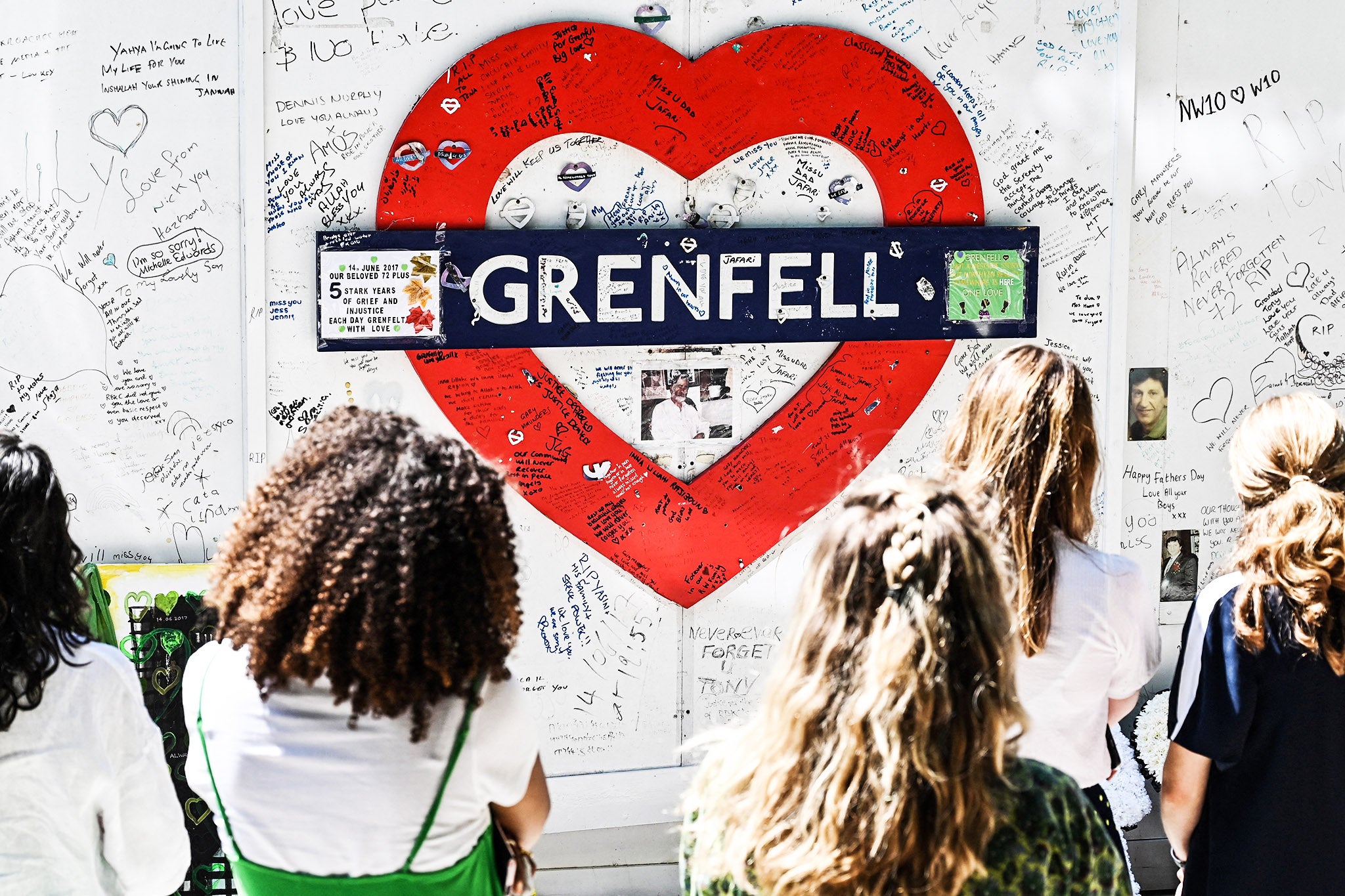 People gather in front of the makeshift memorial created on the wall surrounding Grenfell tower in west London