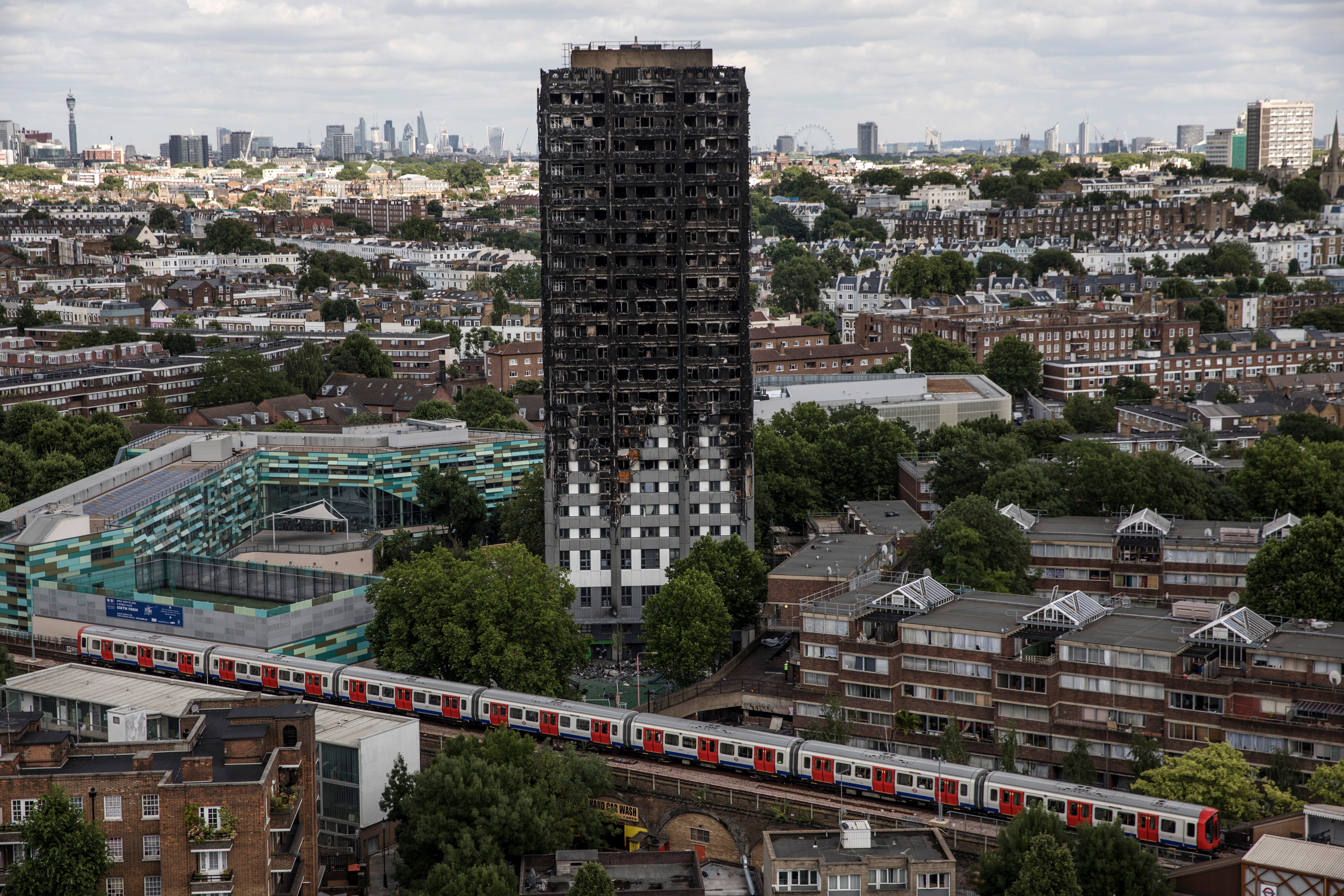 The City of London skyline is seen behind the remains of Grenfell Tower on July 12