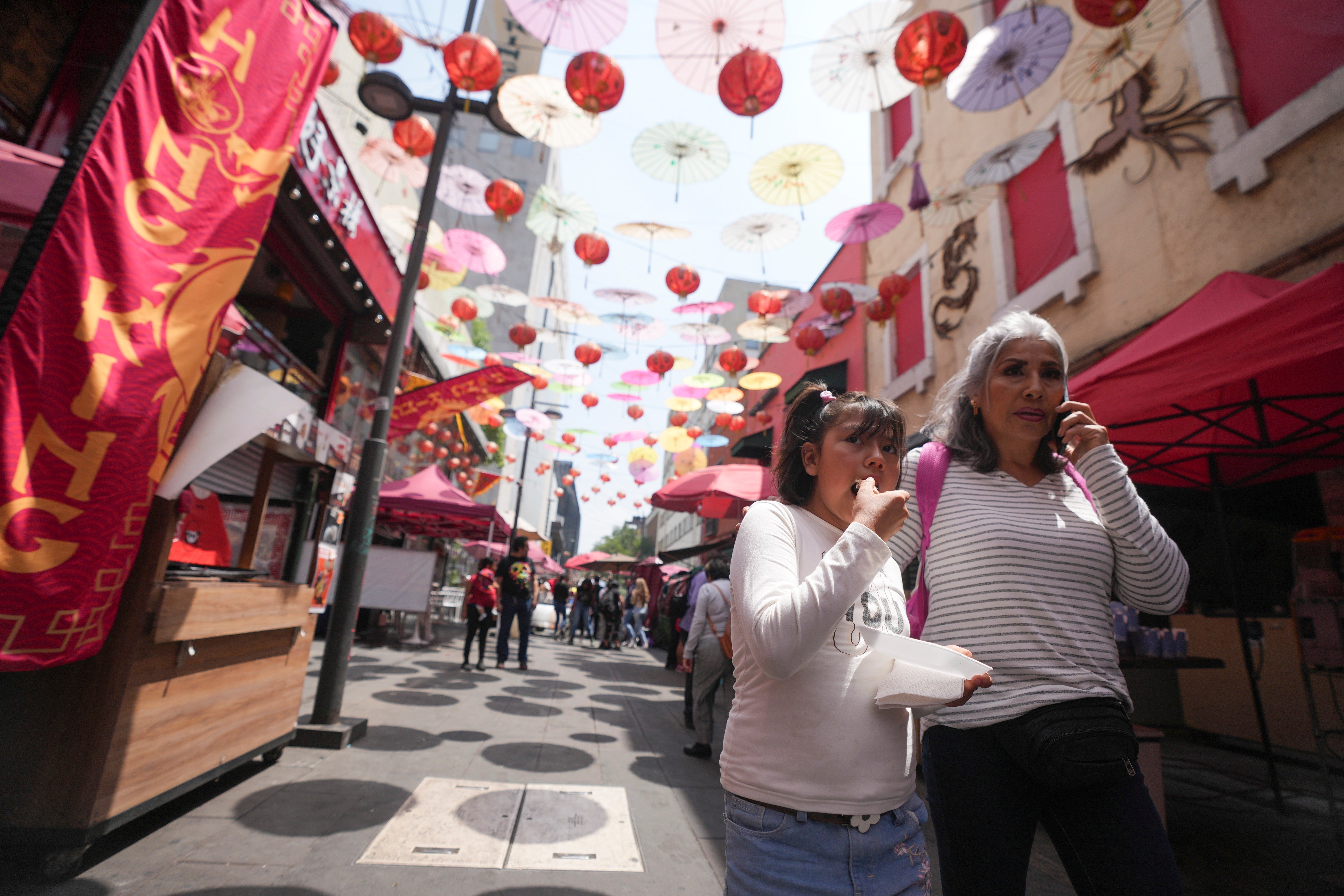 Tourists walk under colorful umbrellas and lanterns at Chinatown in Mexico City's historic center, Saturday, June 8, 2024. (AP Photo/Fernando Llano)
