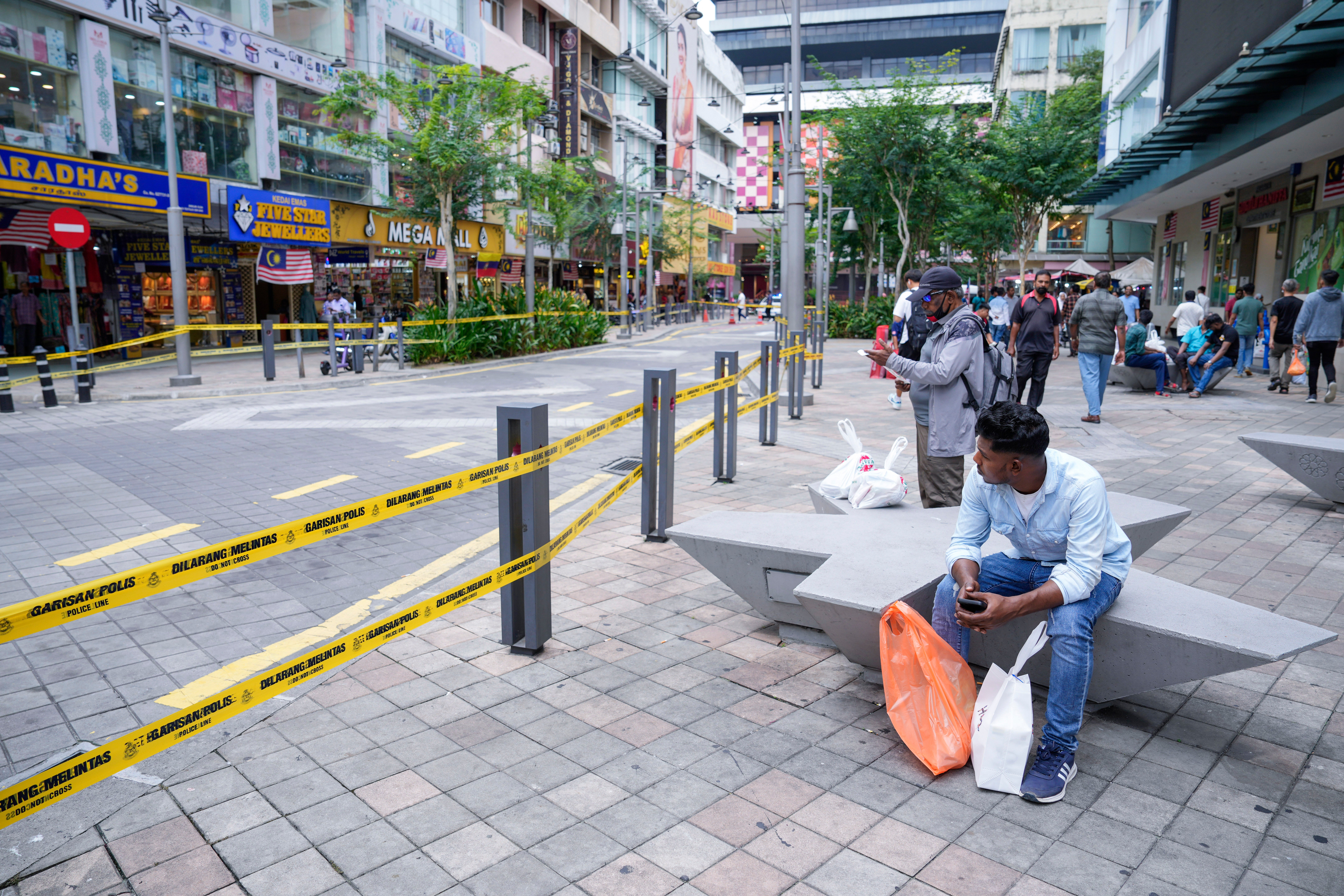 People sit near a closed road after another deep sinkhole appeared a week after a woman fell into a sinkhole in Kuala Lumpur, Malaysia, on 29 August 2024