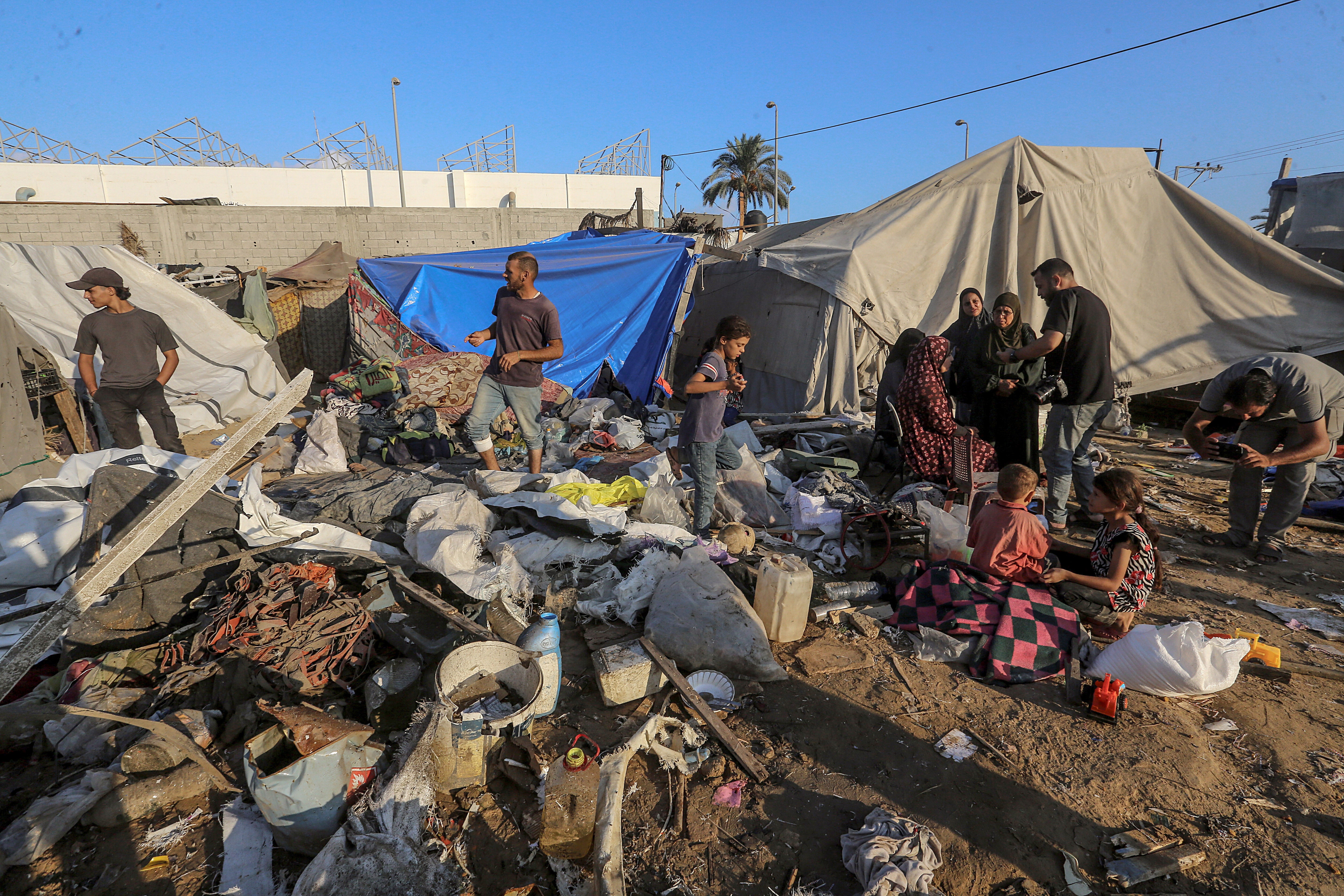 Internally displaced Palestinians inspect their destroyed shelters following a strike in Deir al-Balah