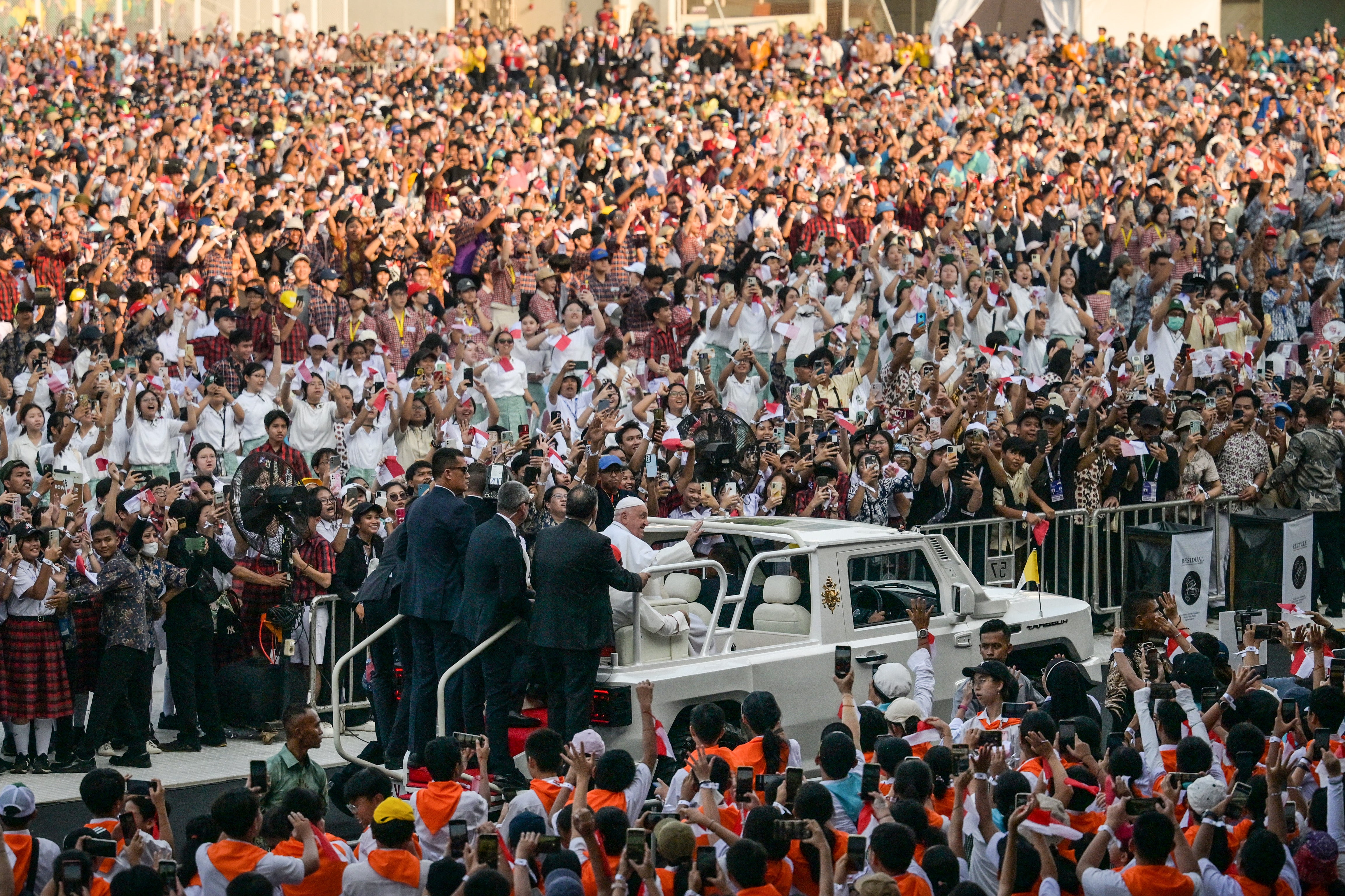 Pope Francis waves to worshippers gathering at Madya stadium on his way to attend the holy mass at the Gelora Bung Karno Stadium in Jakarta