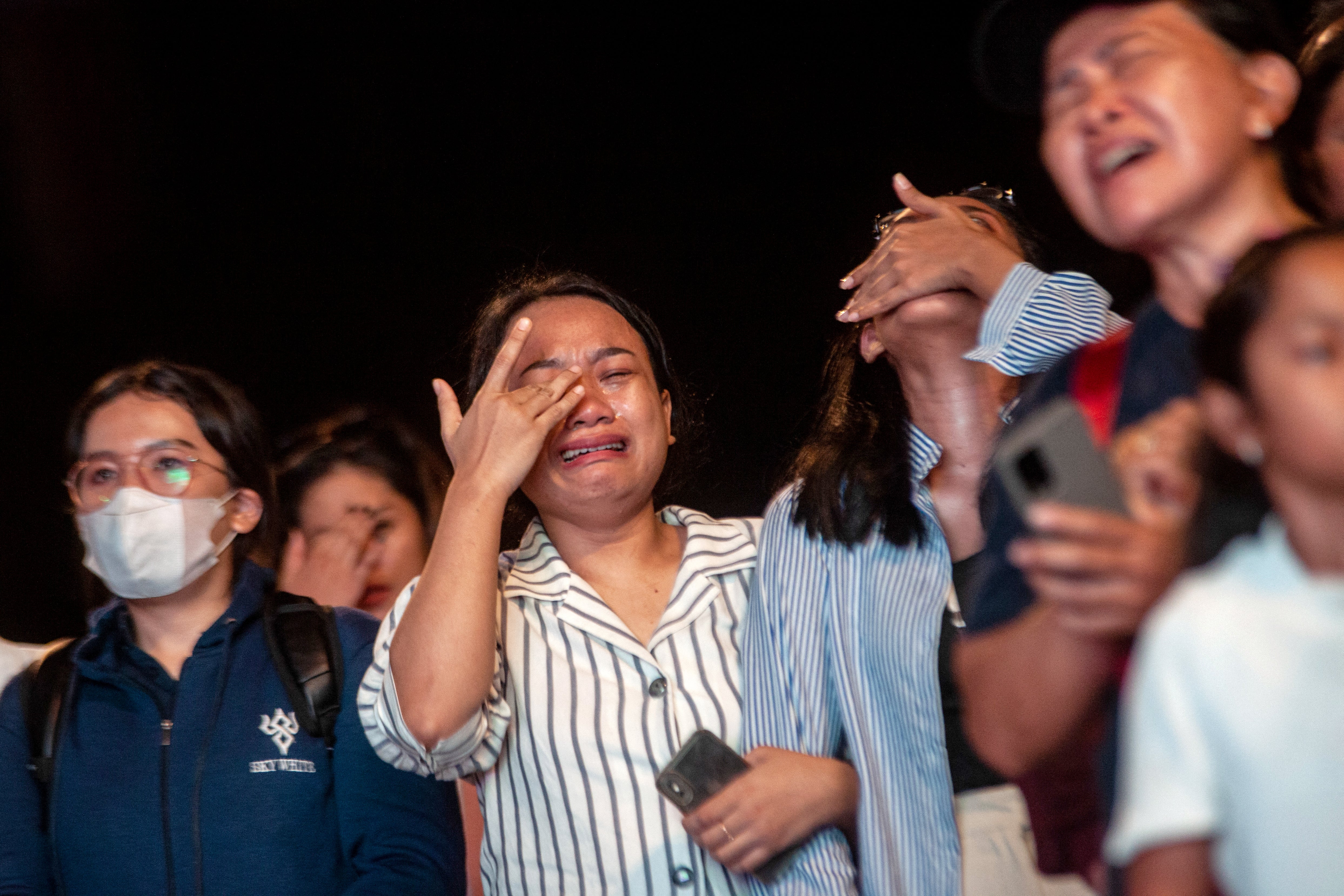 Catholic faithfuls react as they watch an electric screen, live streaming the holy mass led by Pope Francis, outside the Gelora Bung Karno Stadium