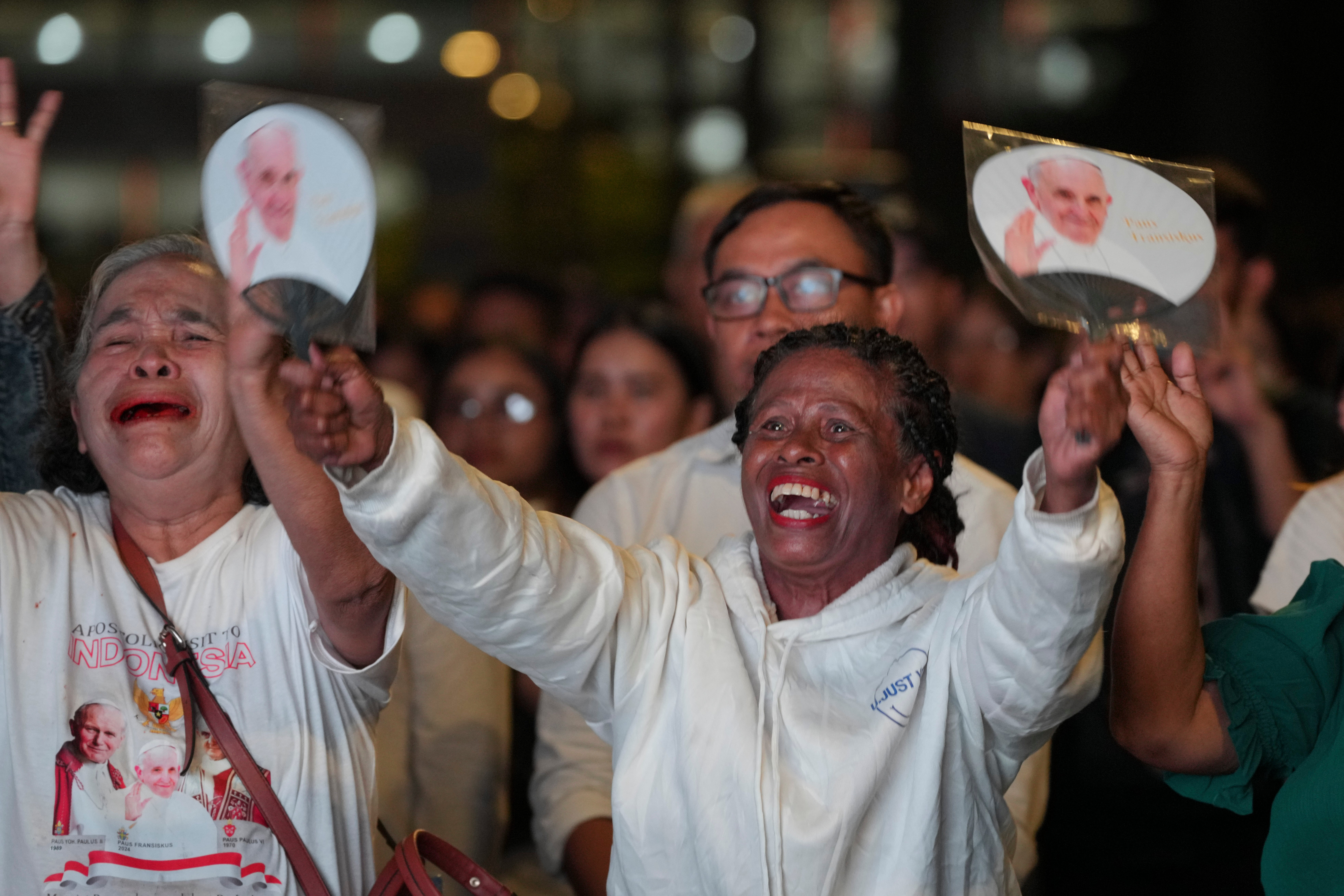 Faithful react as they watch the live screening of the holy mass lead by Pope Francis, outside the Gelora Bung Karno Stadium