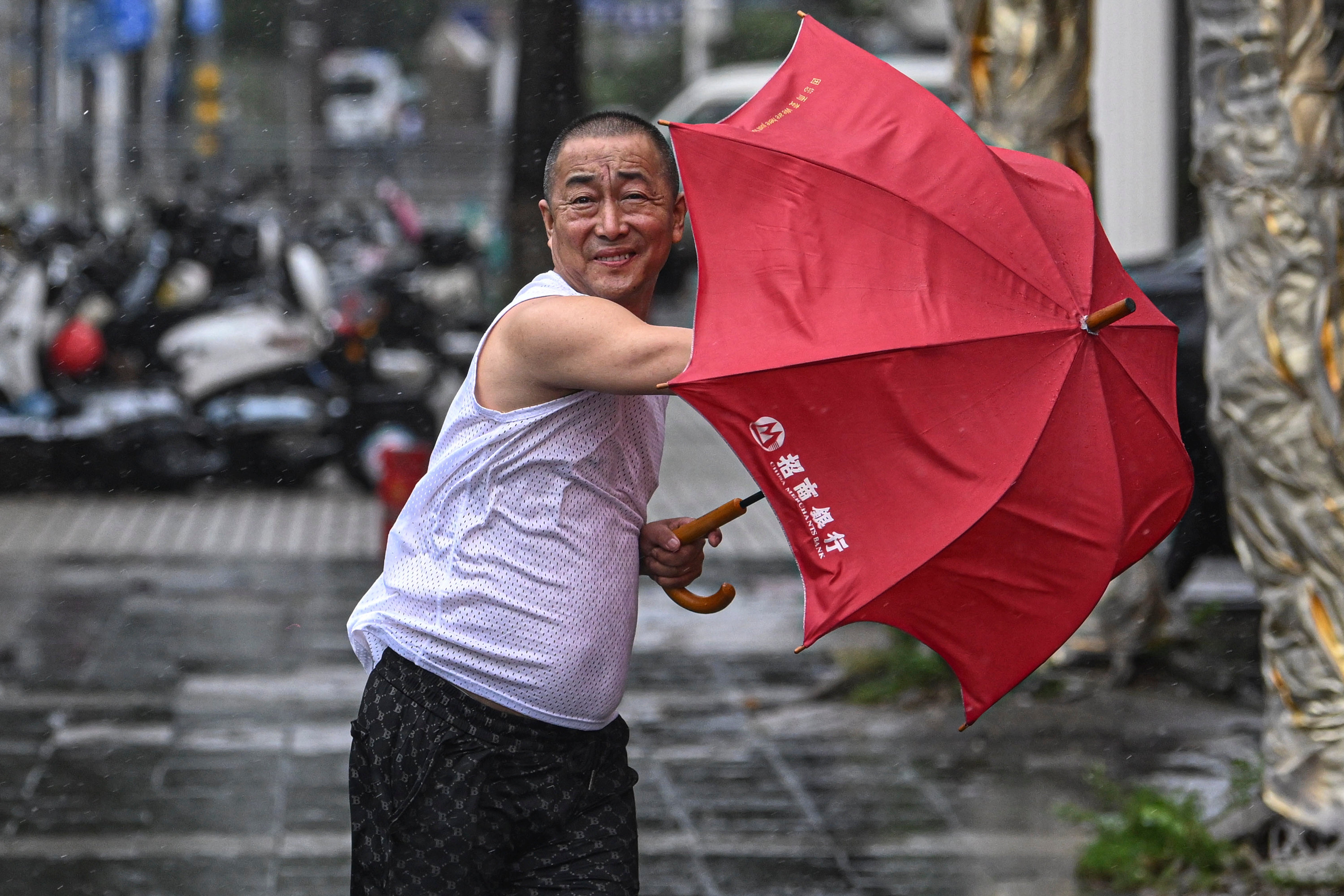 In this photo released by Xinhua News Agency, a man holding an umbrella struggles against the wind following the landfall of typhoon Yagi in Haikou, south China’s Hainan Province, Friday, 6 September 2024