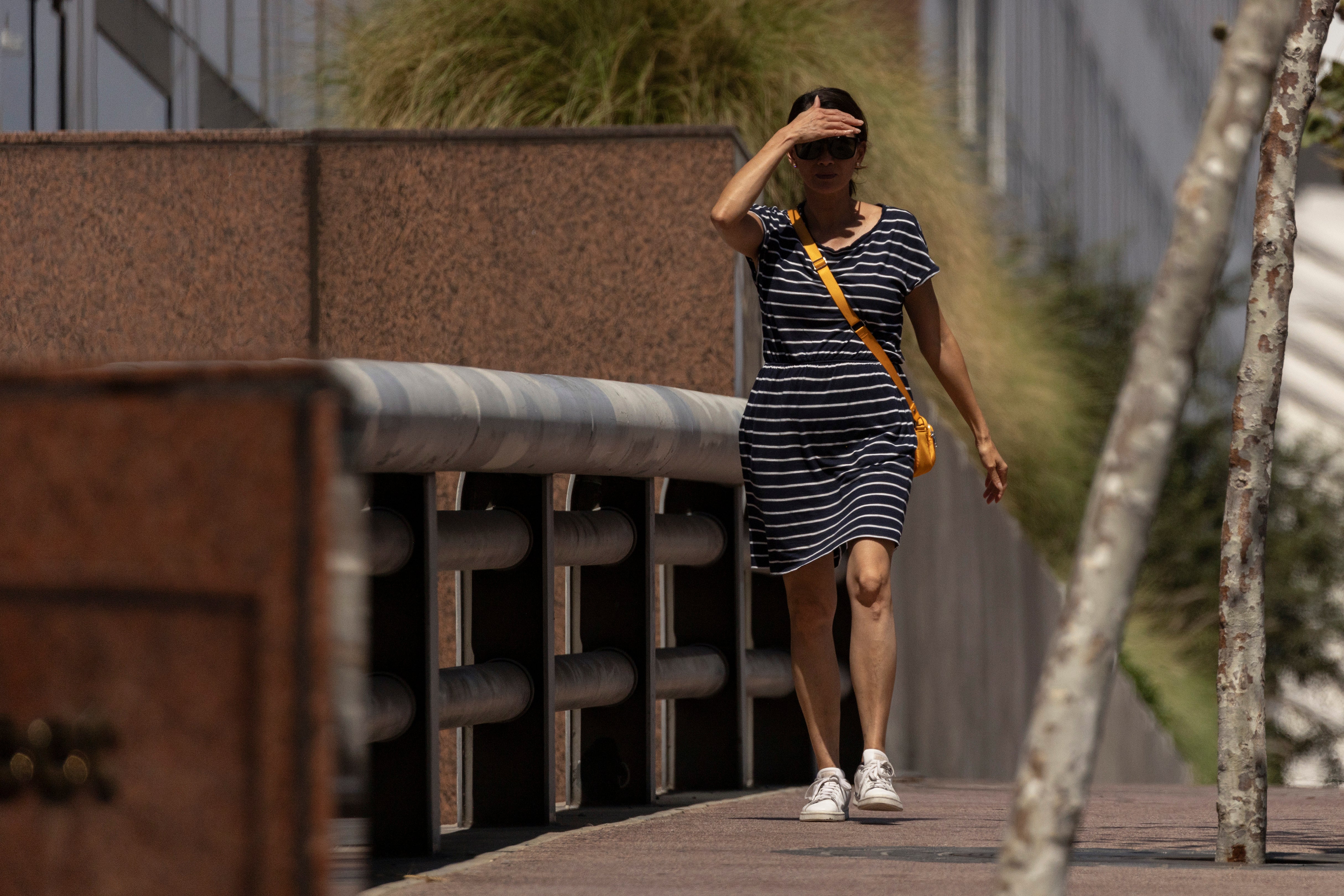 A woman shields her eyes from the sun as she walks in downtown Los Angeles during a heatwave Friday, Sept. 6, 2024