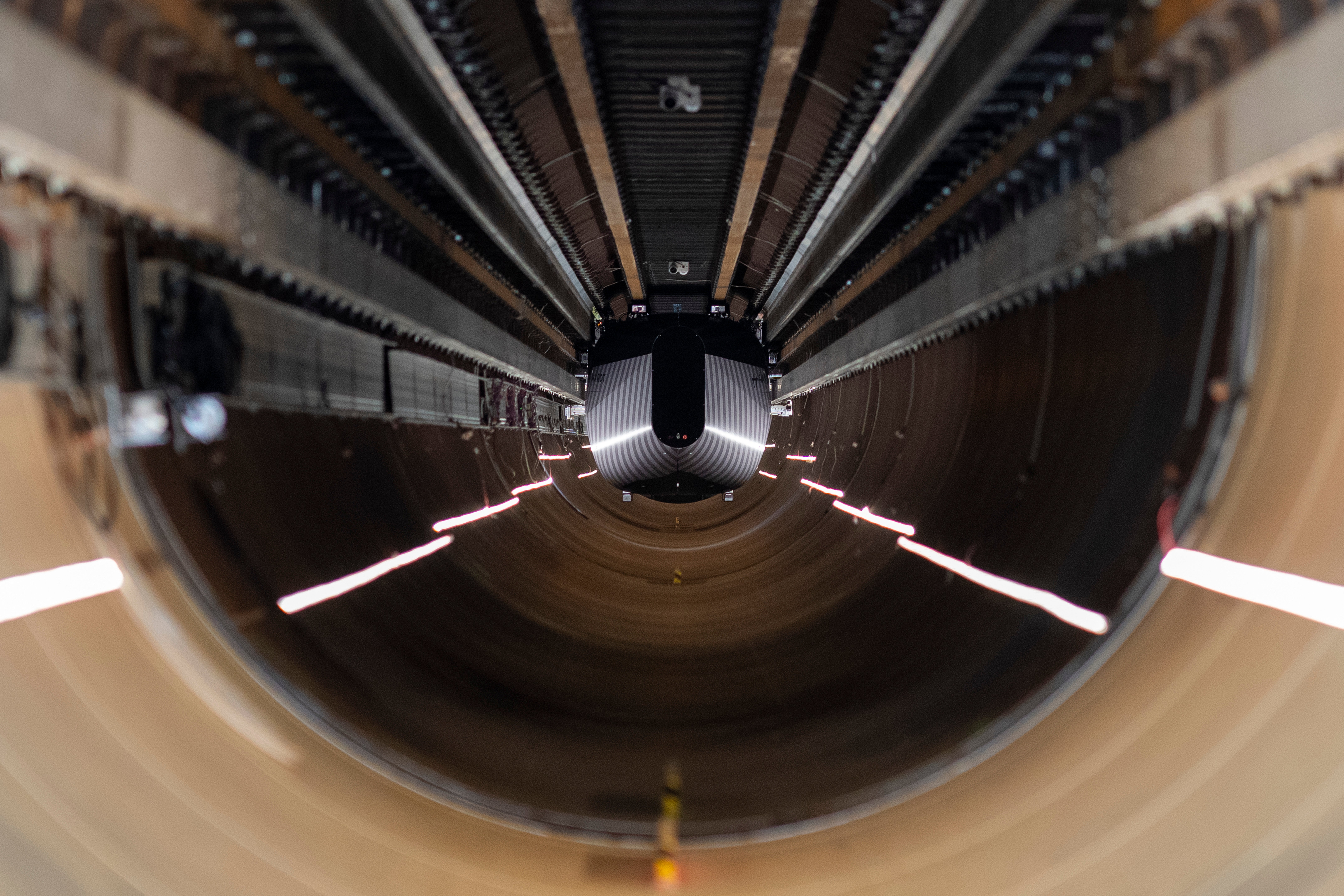 A test vehicle levitated by magnetic fields zips through a depressurized tube in a testing ground for a high-speed transit system during a press tour of a European test center for hyperloop transportation technology in Veendam