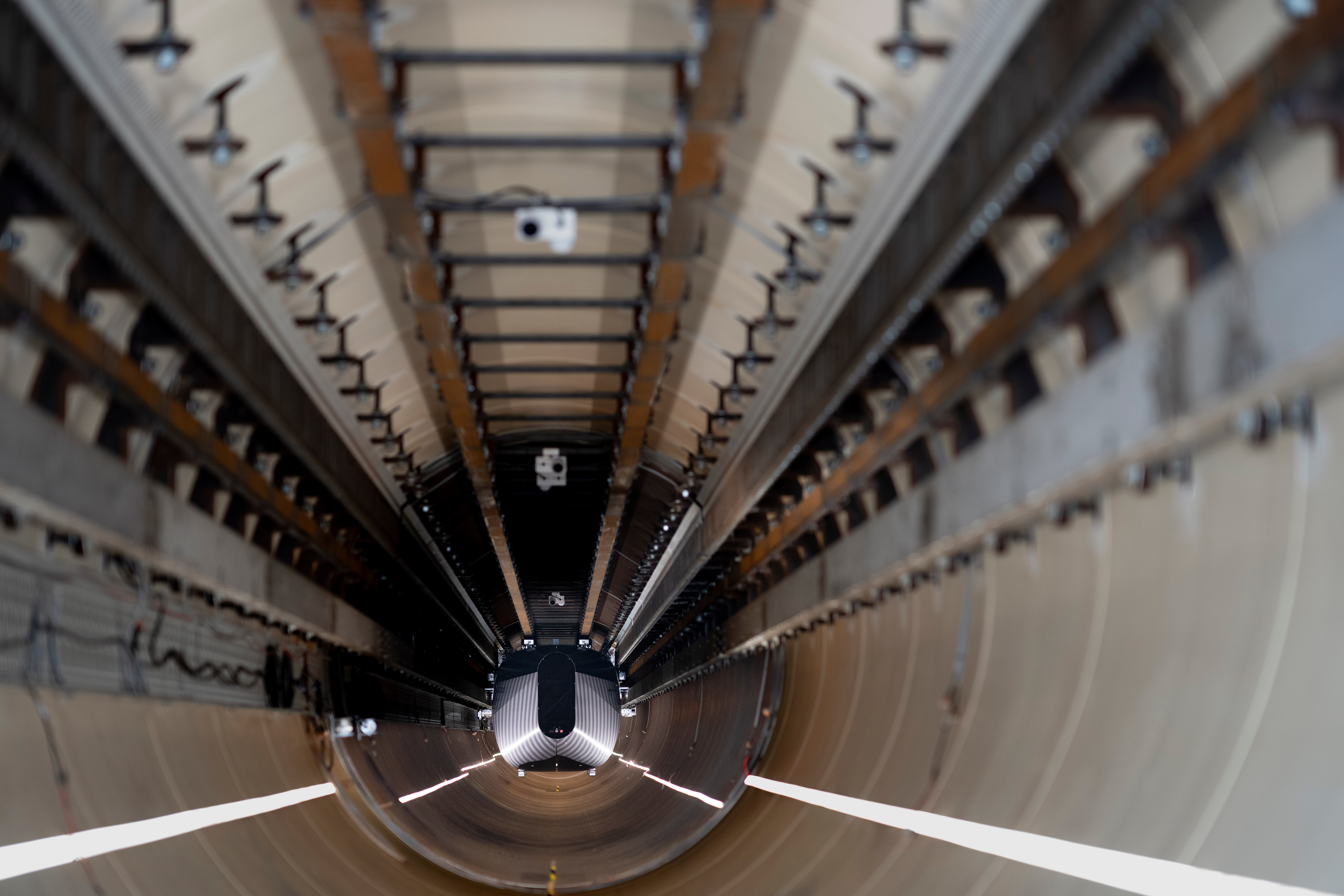 A test vehicle levitated by magnetic fields zips through a depressurized tube in a testing ground