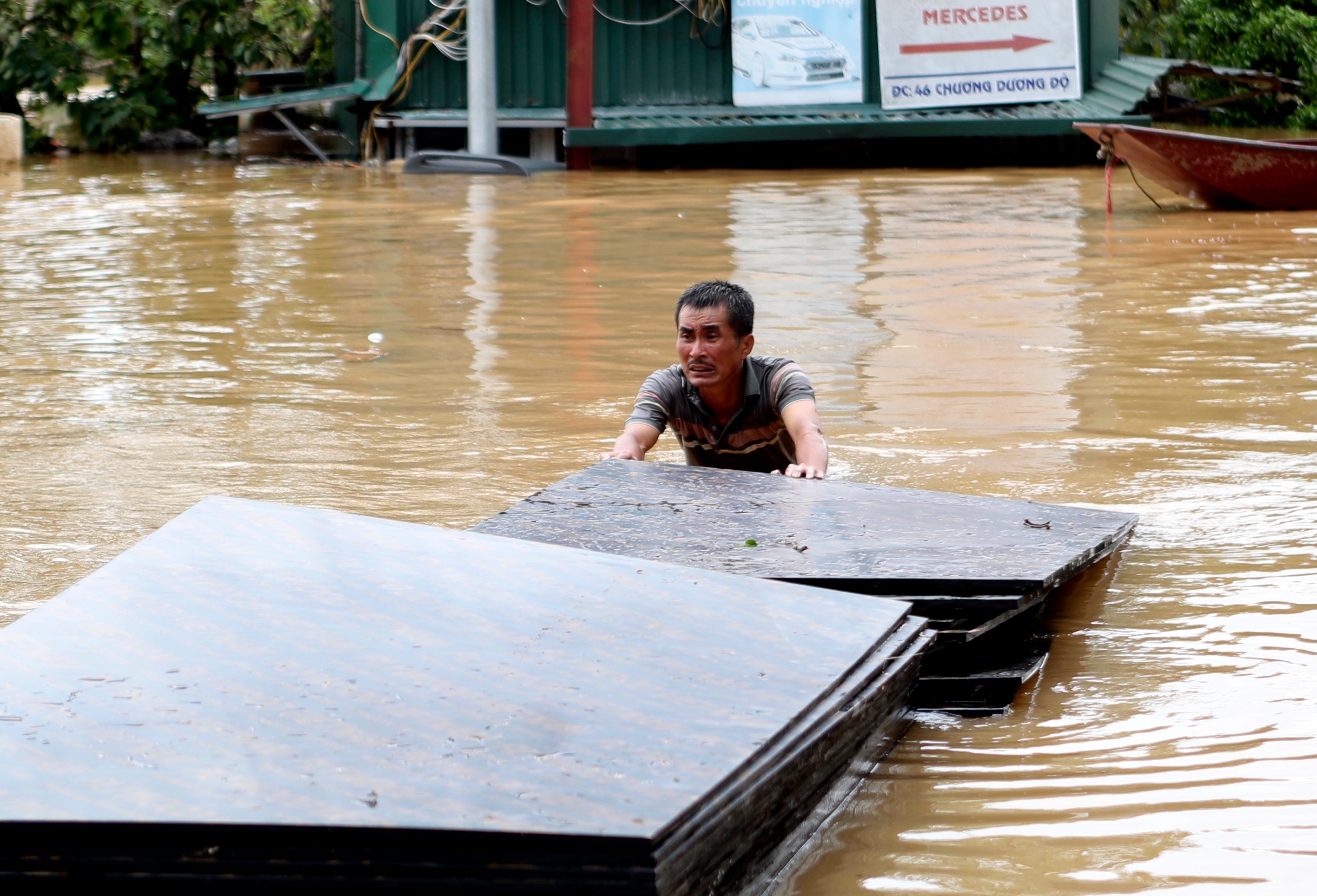 A man pushes a stack of plyboards in flood following Typhoon Yagi in Hanoi, Vietnam on Tuesday