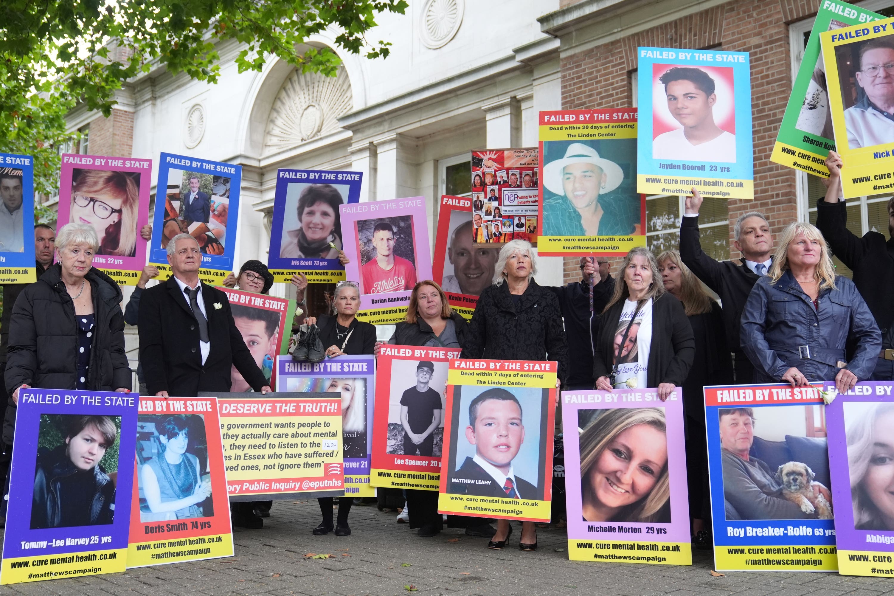 Family members of those lost after receiving treatment for mental health concerns hold up pictures outside the Lampard Inquiry at Chelmsford Civic Centre (Joe Giddens/PA)