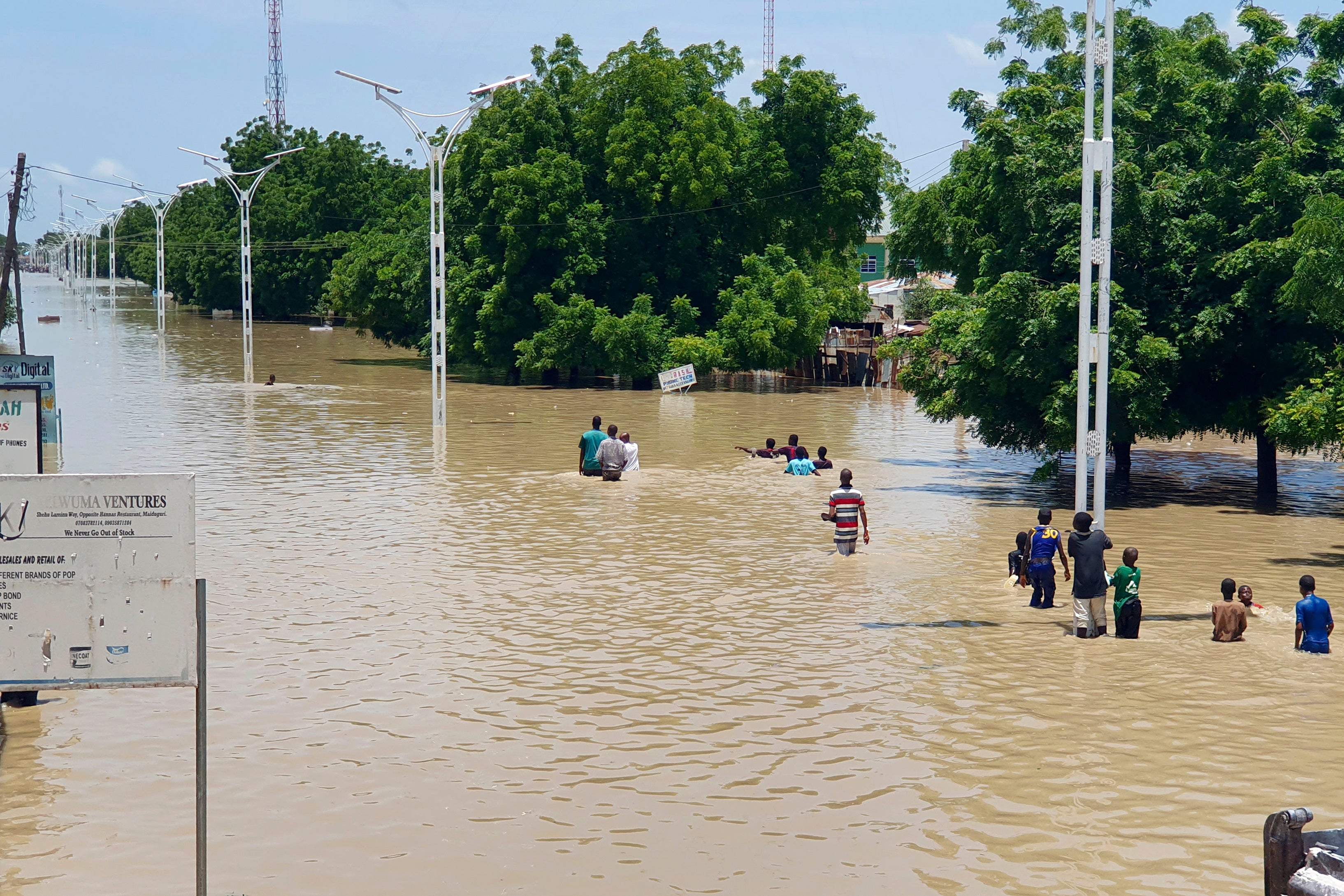 People walk through floodwaters following a dam collapse in Maiduguri, Nigeria