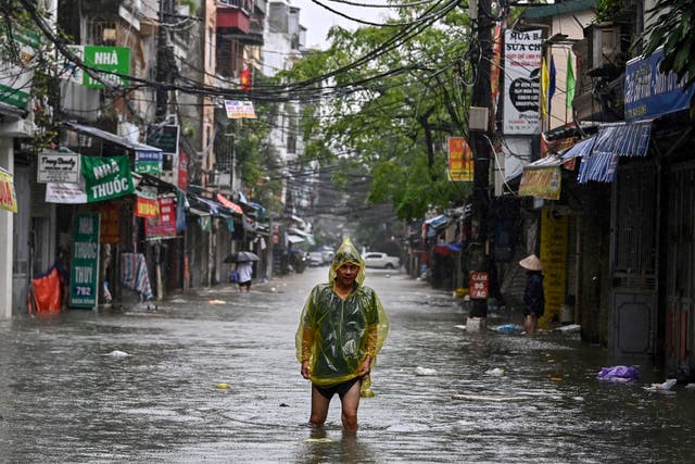 <p>A man wearing a plastic poncho wades through flood waters on a street in Hanoi as heavy rains in the aftermath of Typhoon Yagi brought flooding to northern Vietnam</p>