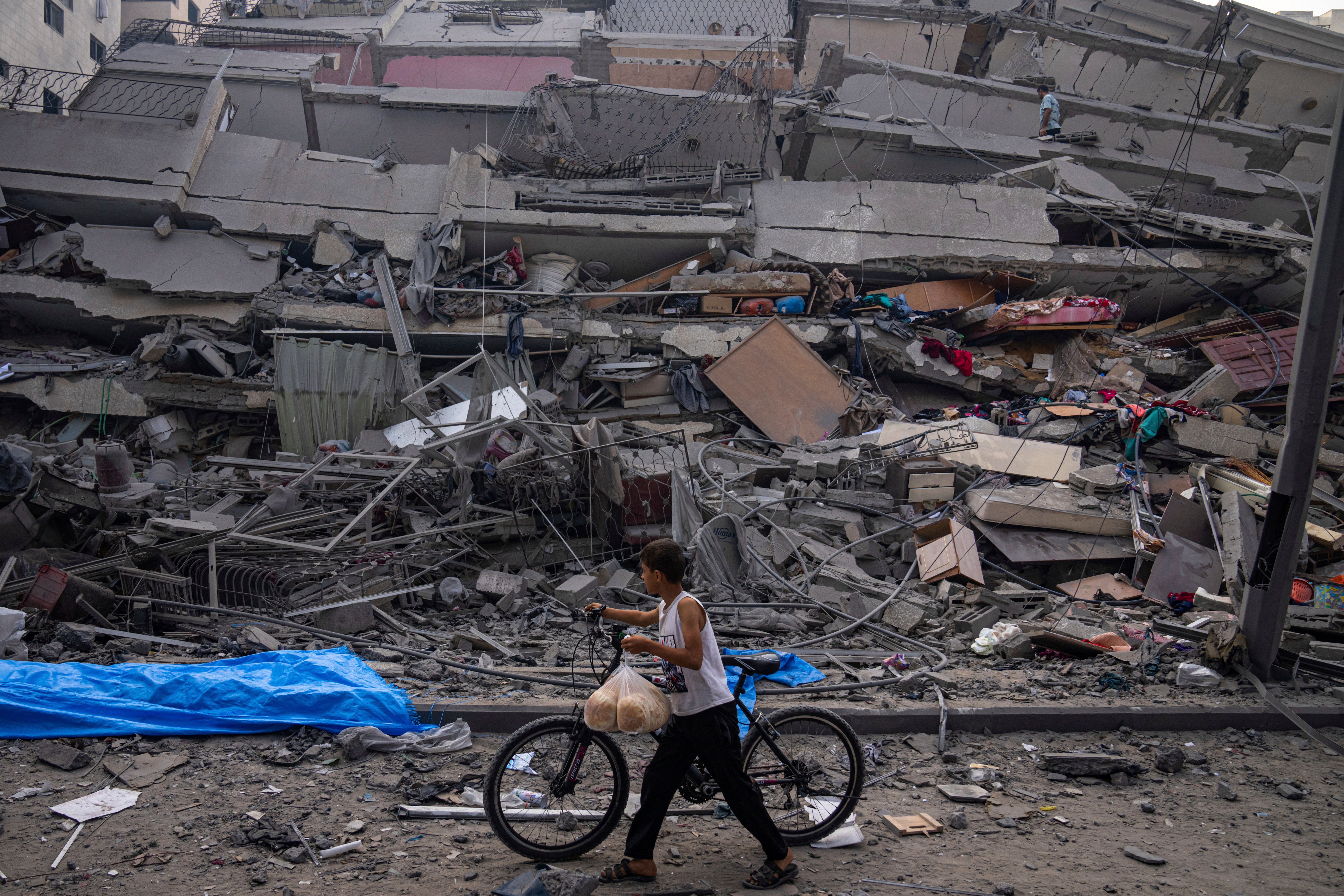 A Palestinian child walks with a bicycle by the rubble of a building after it was hit by an Israeli airstrike, in Gaza City, Oct. 8, 2023