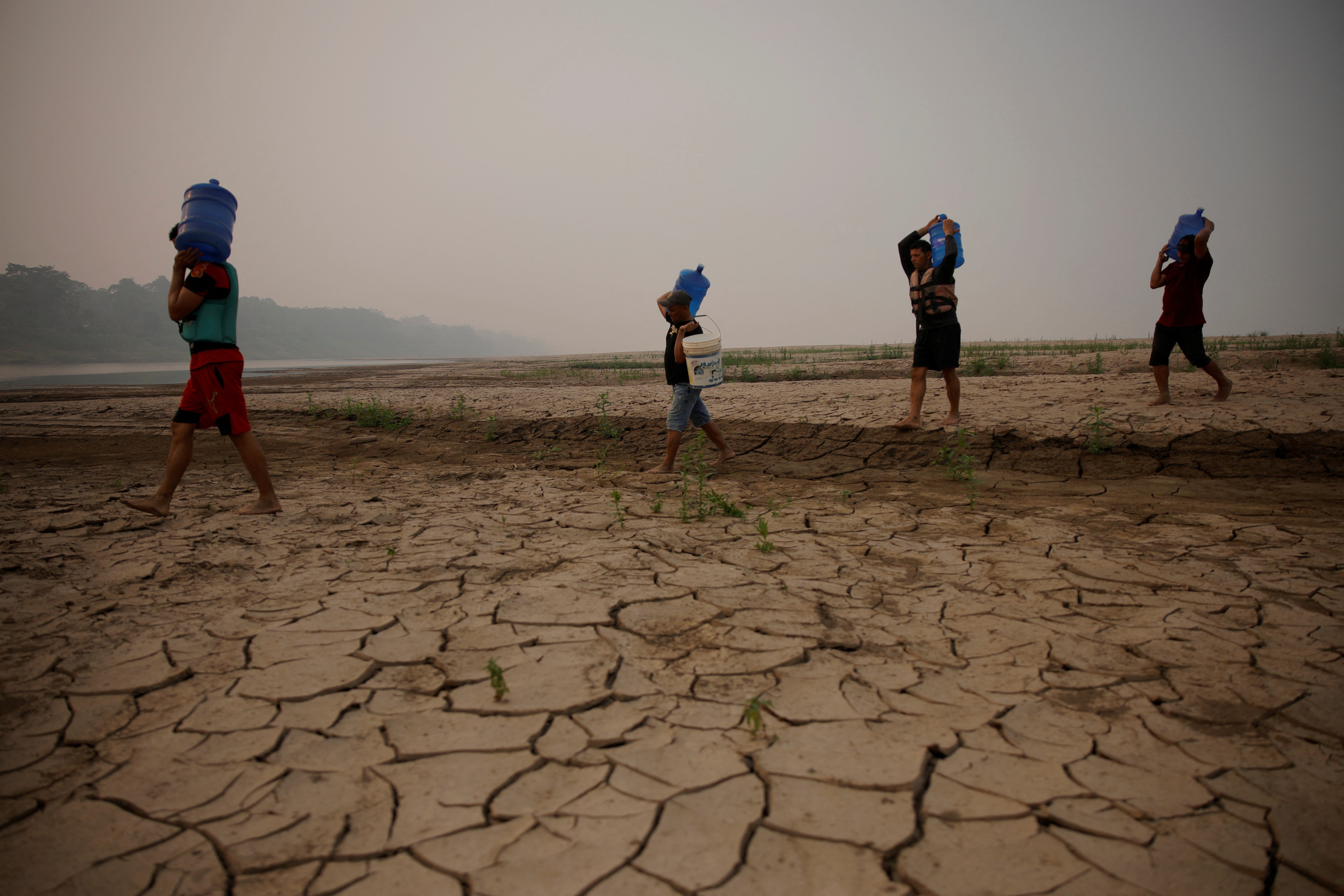 River dwellers carry water on the sandbanks of Brazil’s Madeira river last September. The country was threatened by widespread drought and wildfires this summer. A new UN report details the “catastrophic” rise in temperatures