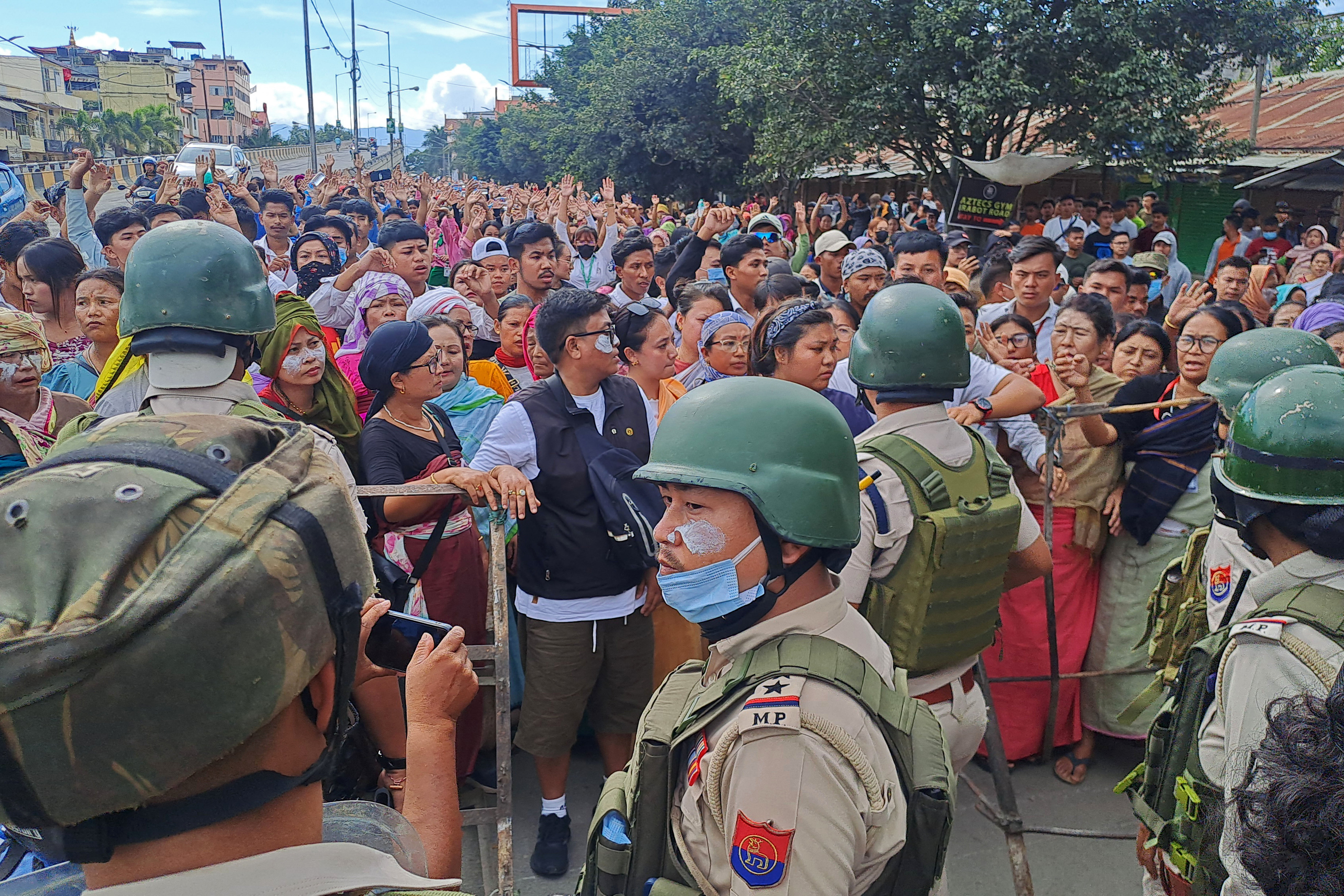 Protesters gather as security personnel block their way along a street during a curfew in Imphal on 10 September 2024