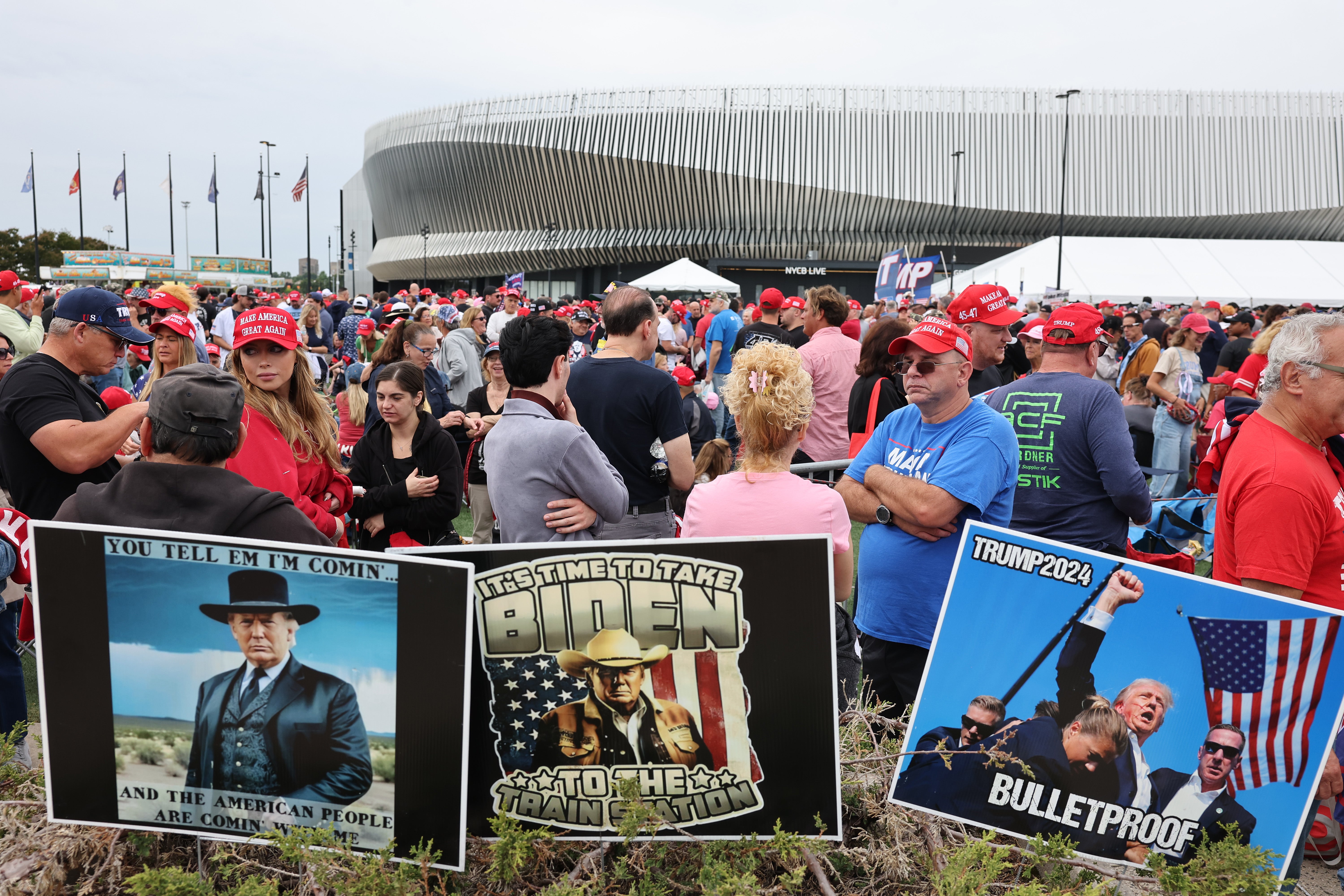 Supporters of Trump wait for his rally to begin on Wednesda. Large posters next to the crowd portray Trump — who famously resided in a gilded New York penthouse between 1983 and 2019 — as a rough-and-tumble cowboy