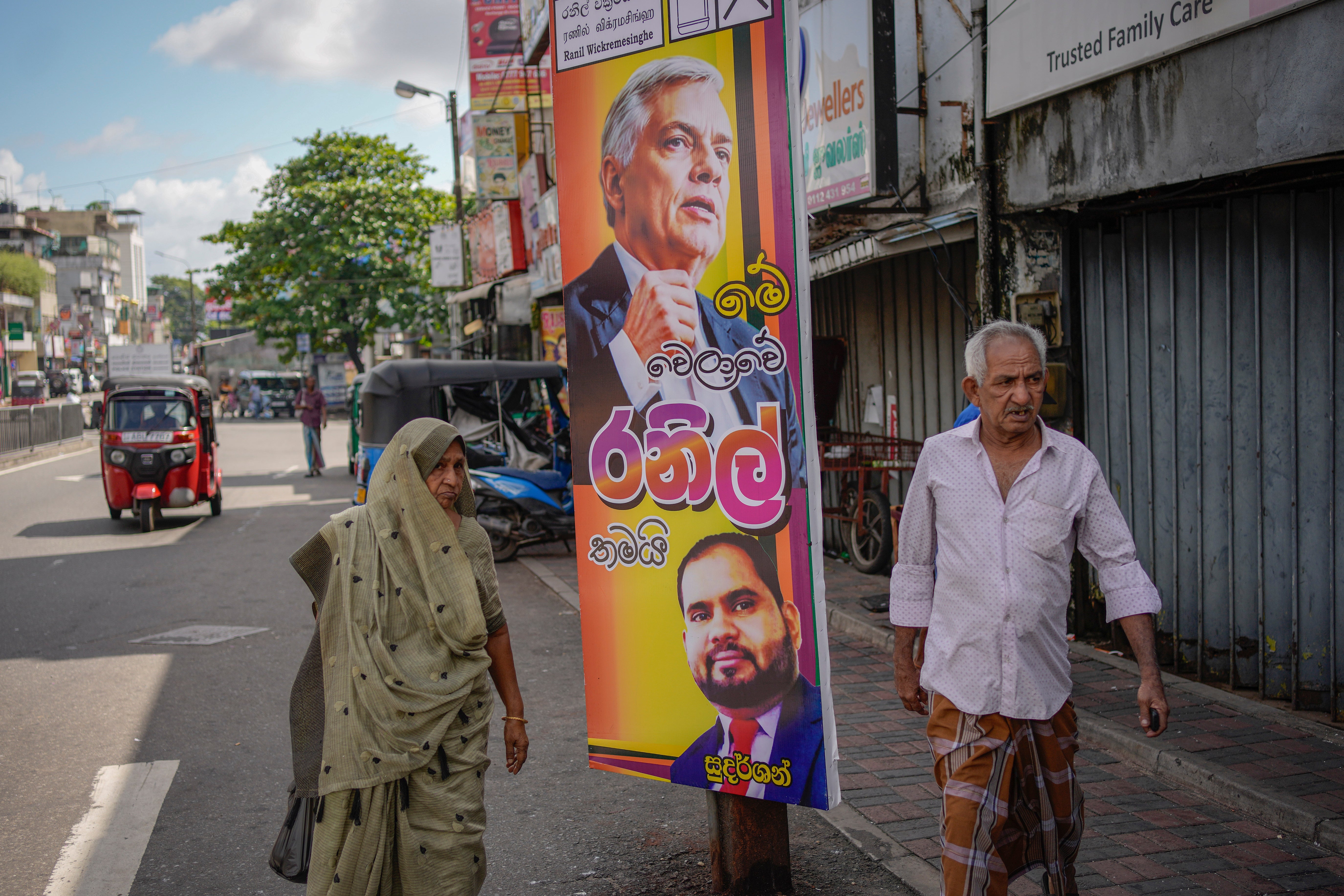 A couple walks past an election poster showing a portrait of Sri Lankan president Ranil Wickremesinghe in Colombo