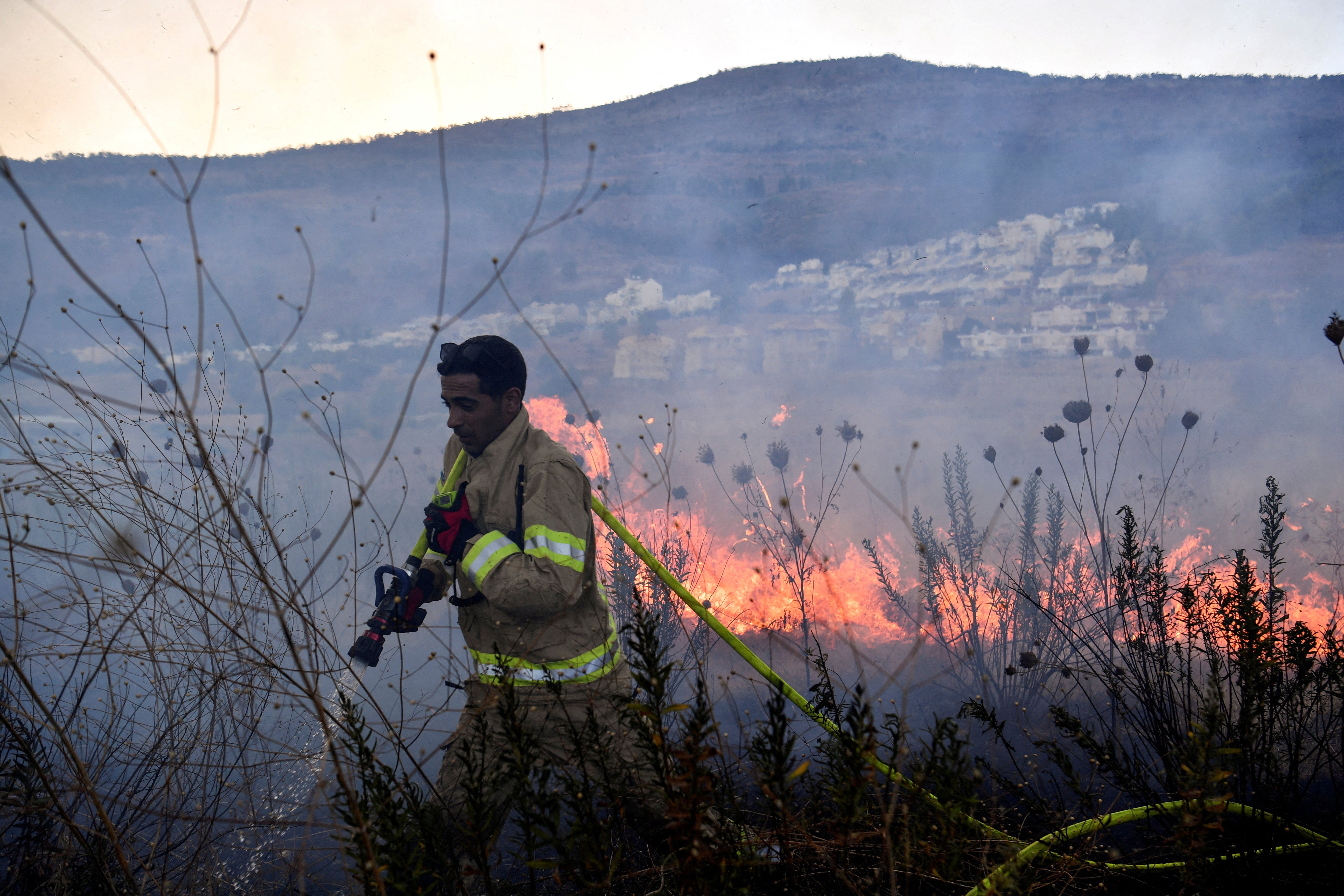 A firefighter works to put out a blaze after rockets were fired from Lebanon towards Israel